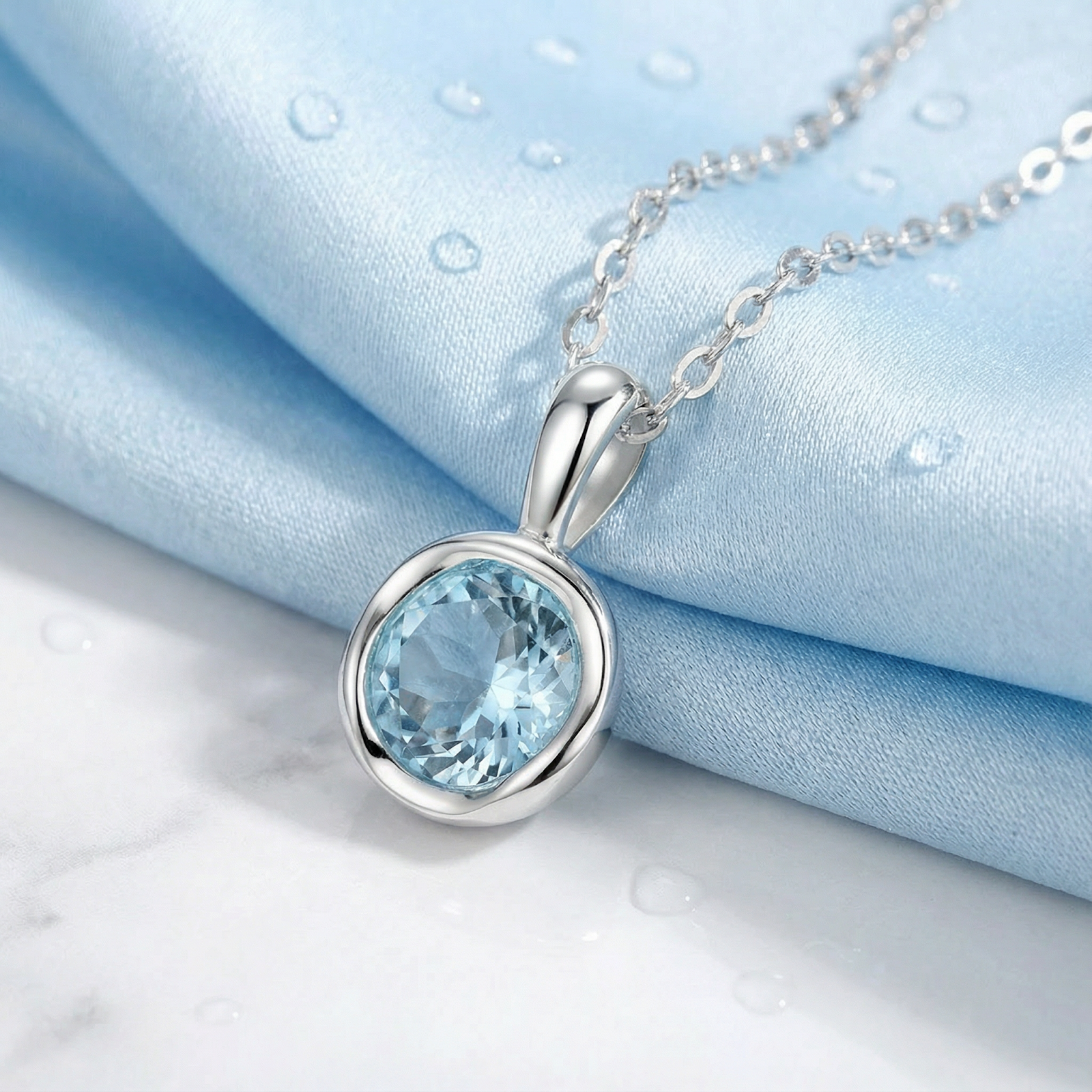 Silver-toned necklace with a round light-blue gemstone pendant on light-blue satin fabric