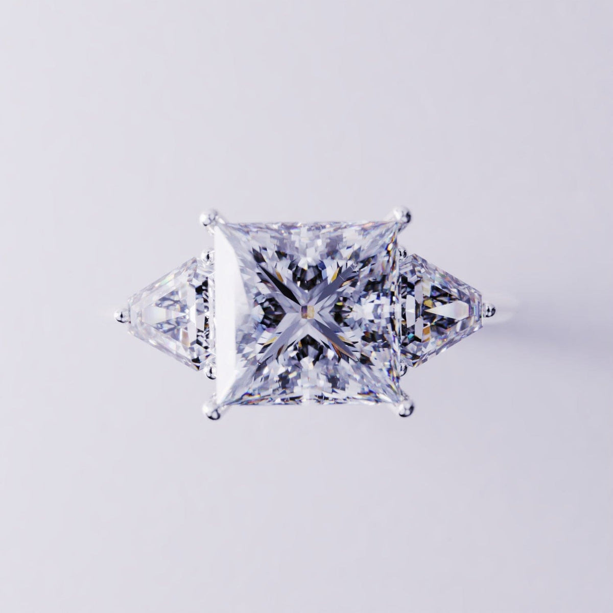 Silver-toned three-stone ring with a central princess-cut square stone flanked by two triangular side stones.