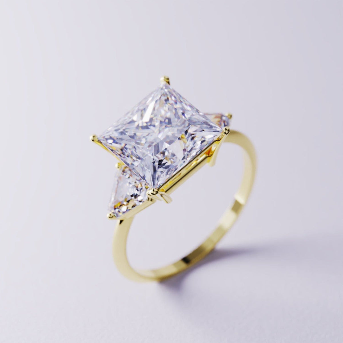 Gold-toned three-stone ring featuring a large square clear stone and two triangular side stones.
