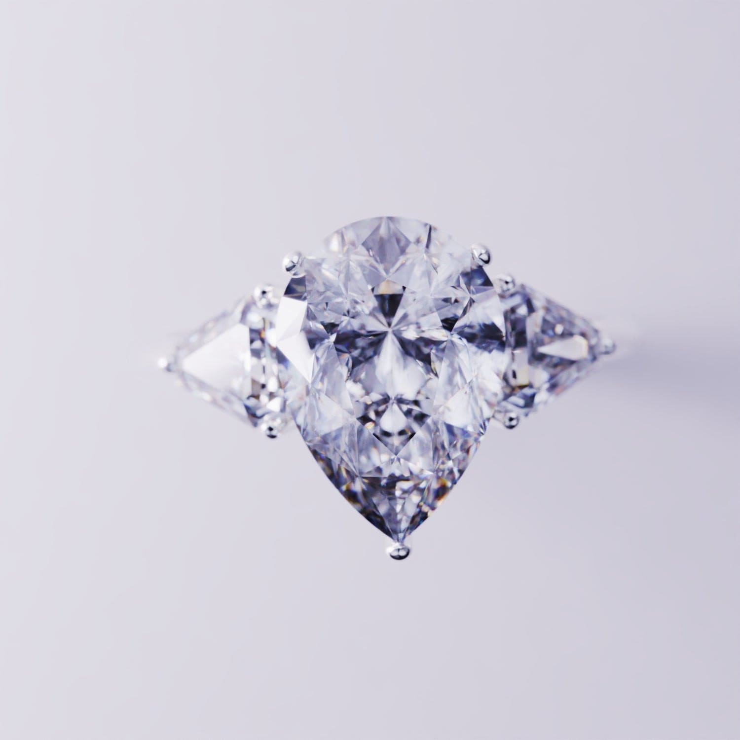 Silver-toned ring with a large pear-shaped center gemstone flanked by two triangular side stones.