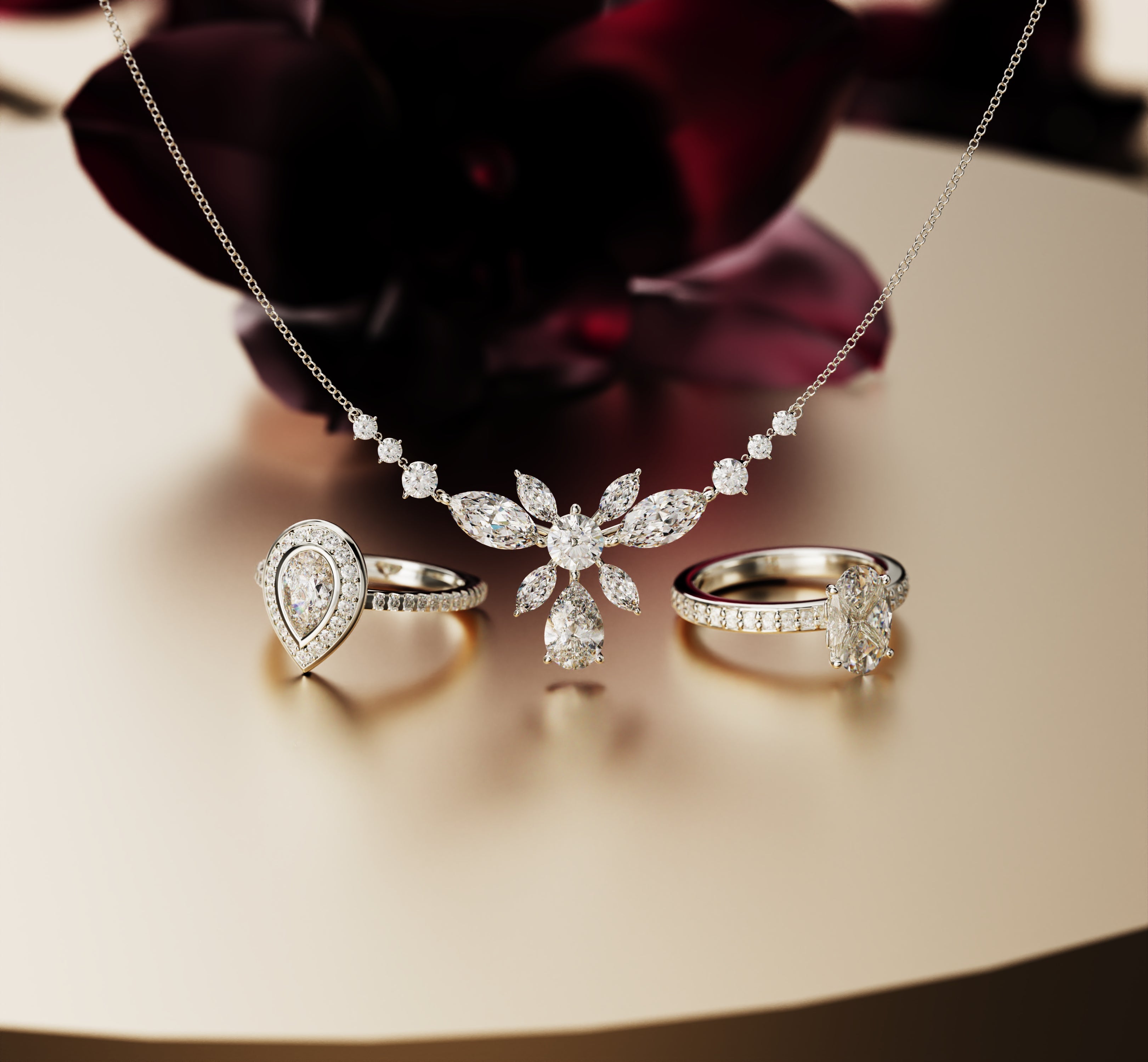 Silver-toned necklace with a floral cluster of clear stones and two matching rings on a reflective surface.
