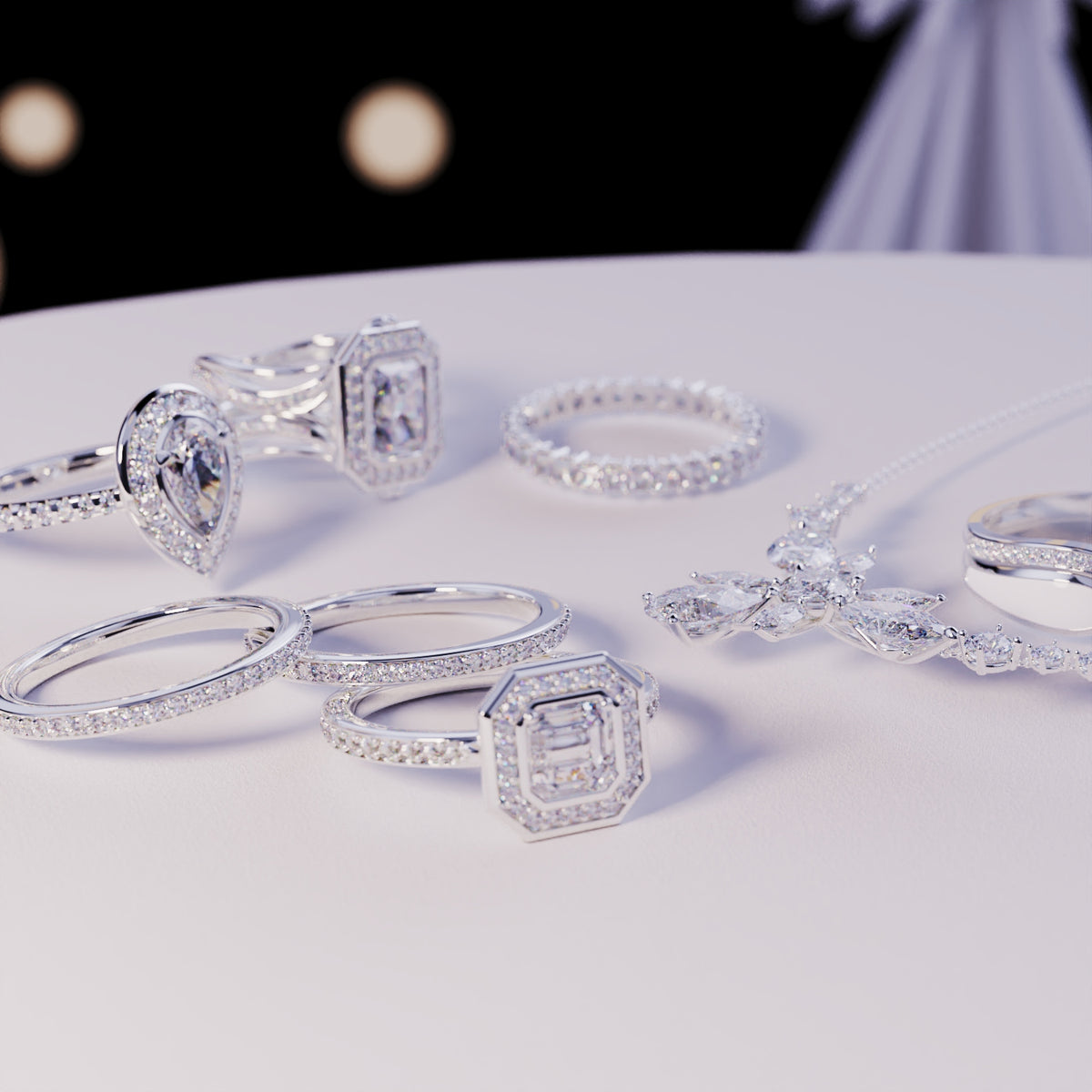 Silver-toned rings and a sparkling pendant necklace with clear faceted accents on a white surface.