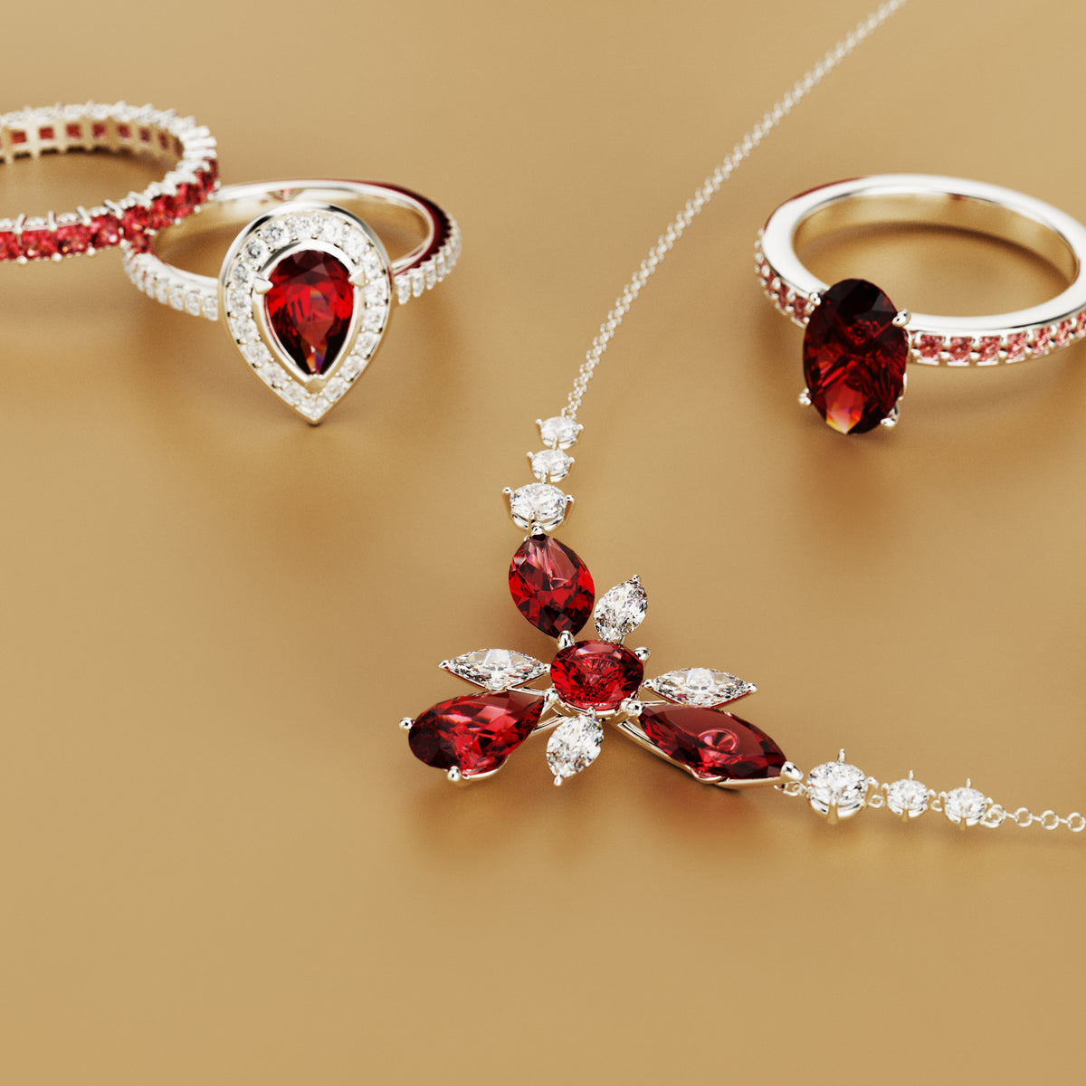 Silver-toned necklace and three rings with red and clear stones on a beige background.