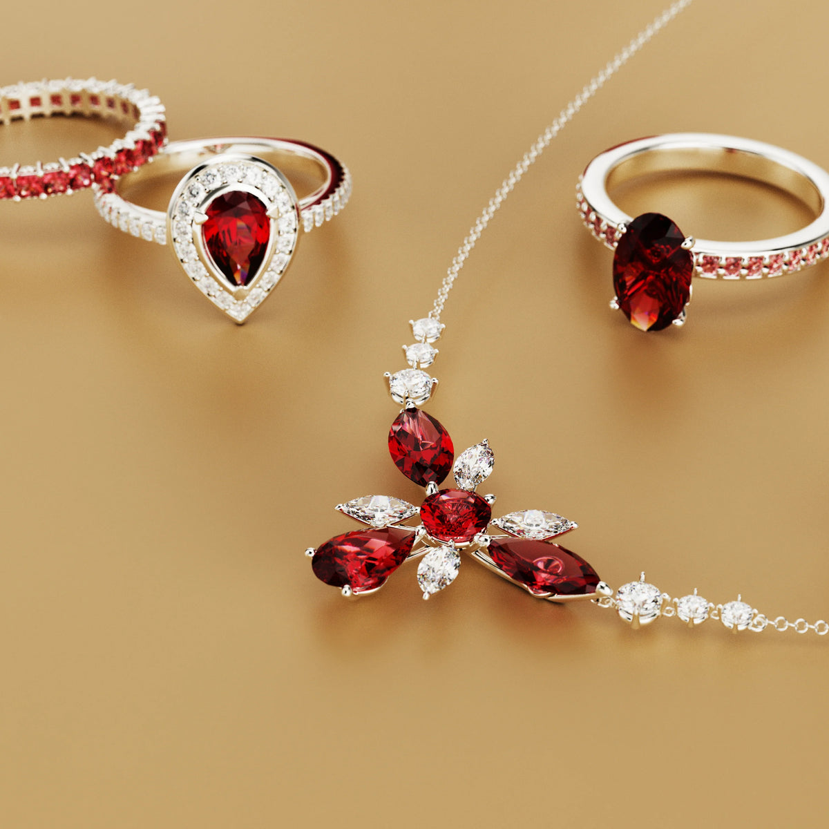 Silver-toned rings and a flower-shaped pendant necklace set with deep red and clear stones on a tan background.