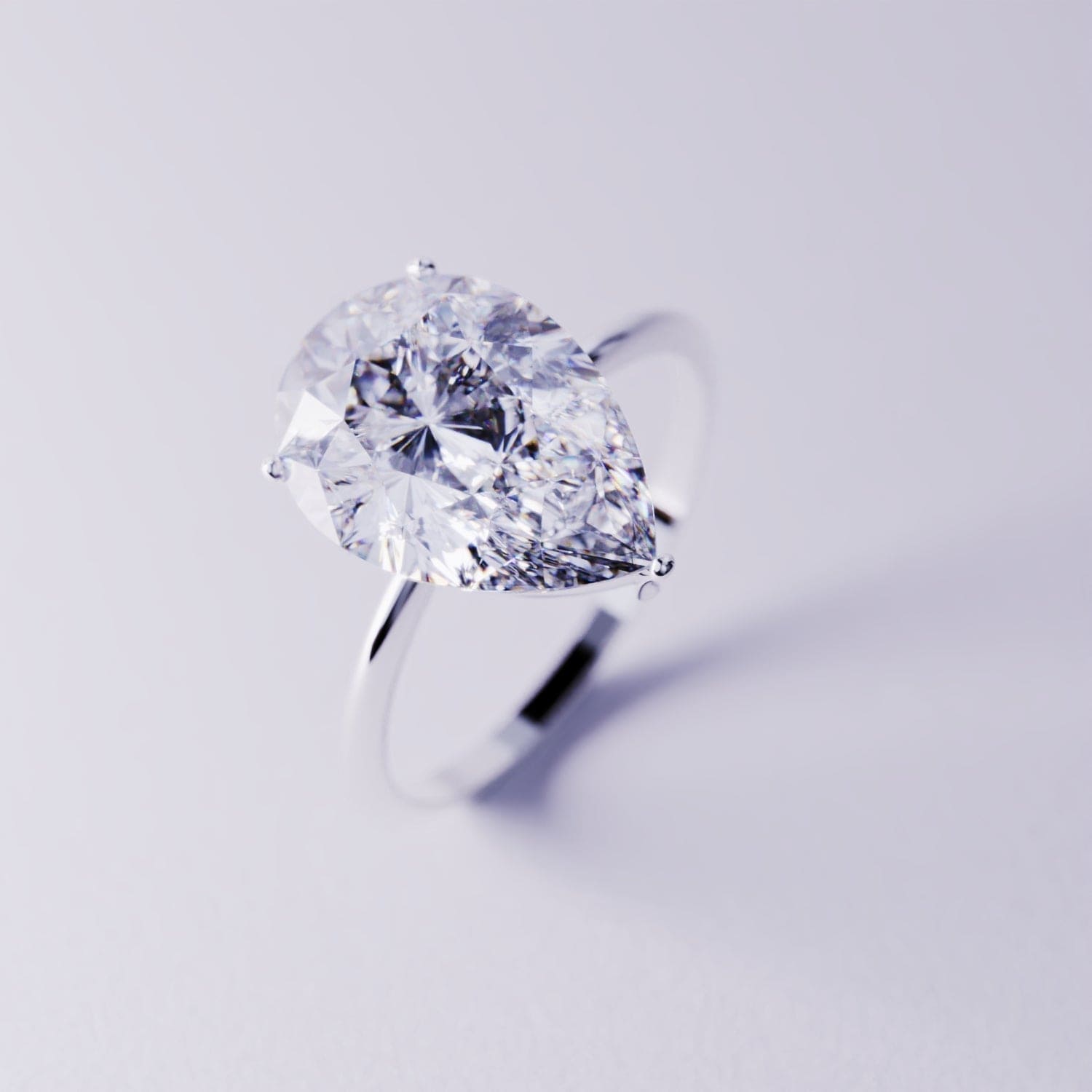 Silver-toned ring with a large pear-cut clear gemstone on a thin band.