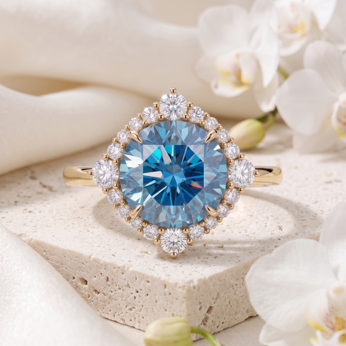 A yellow gold engagement ring featuring a round blue moissanite center stone with a diamond halo on a stone pedestal.
