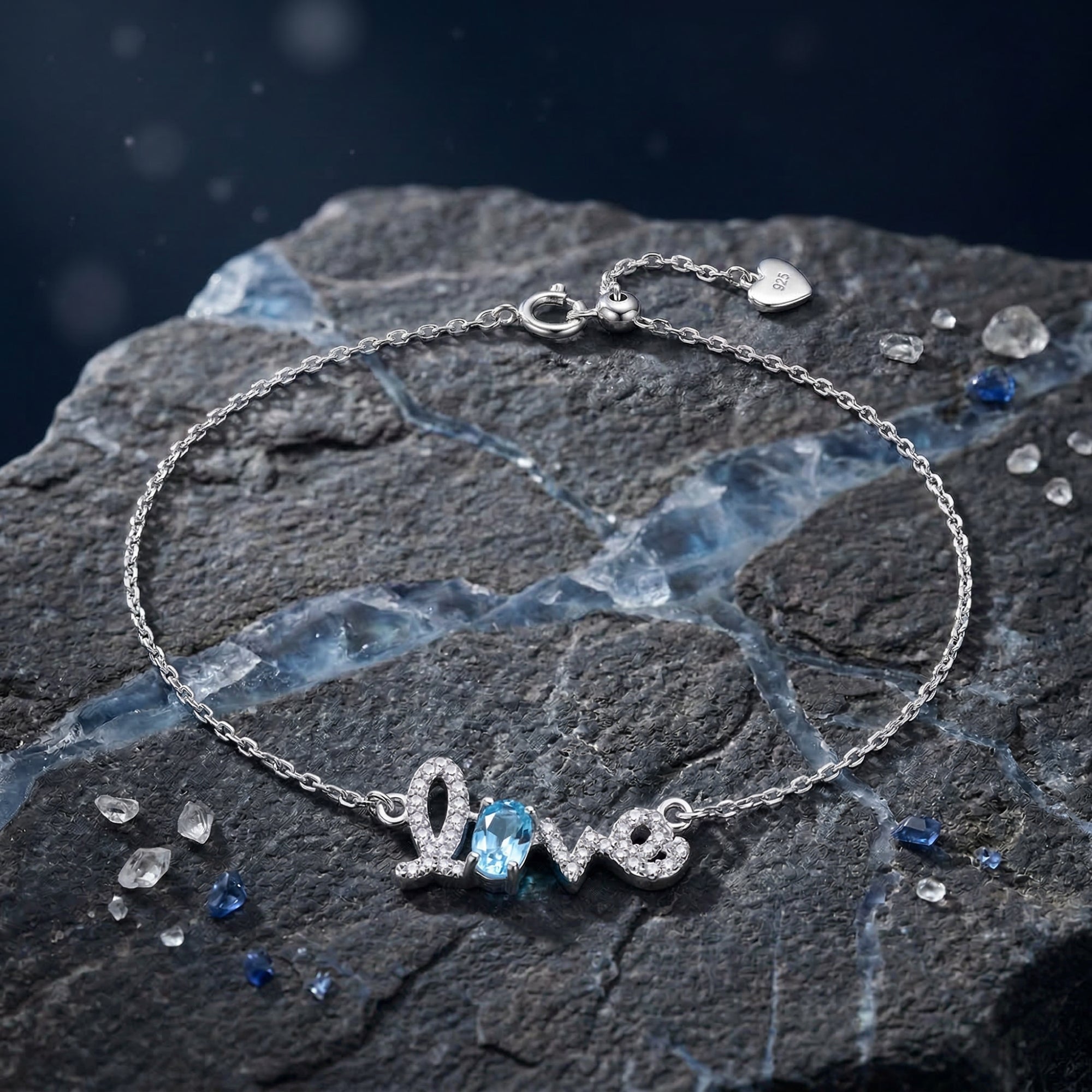 Silver Swiss Blue Topaz Love bracelet with an oval cut gemstone displayed on a dark textured rock.