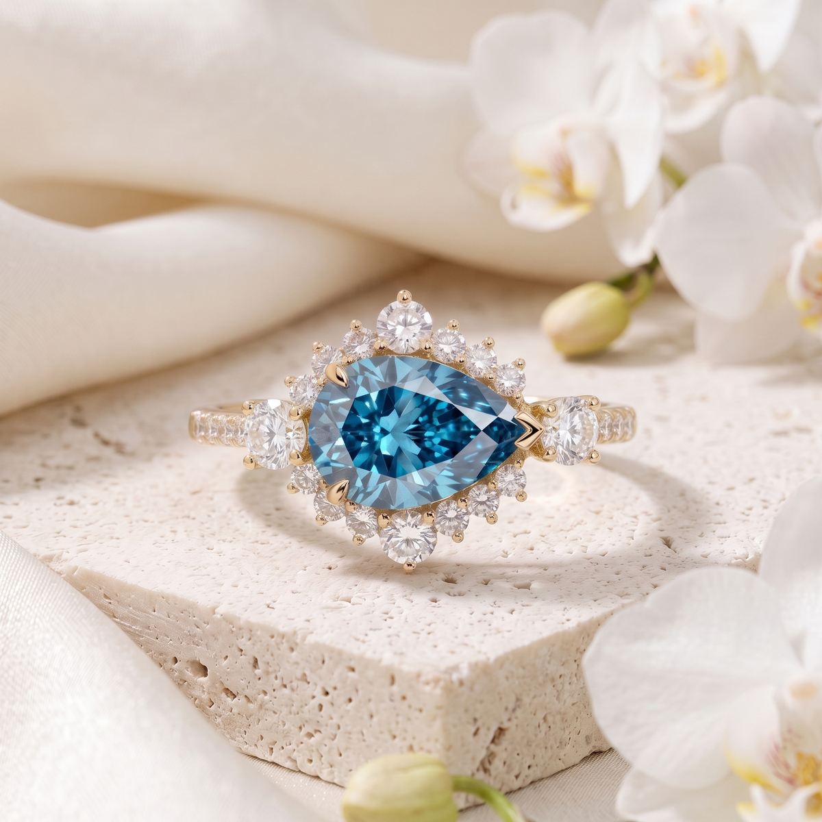 Vintage pear cut blue moissanite halo engagement ring in yellow gold on a stone display.