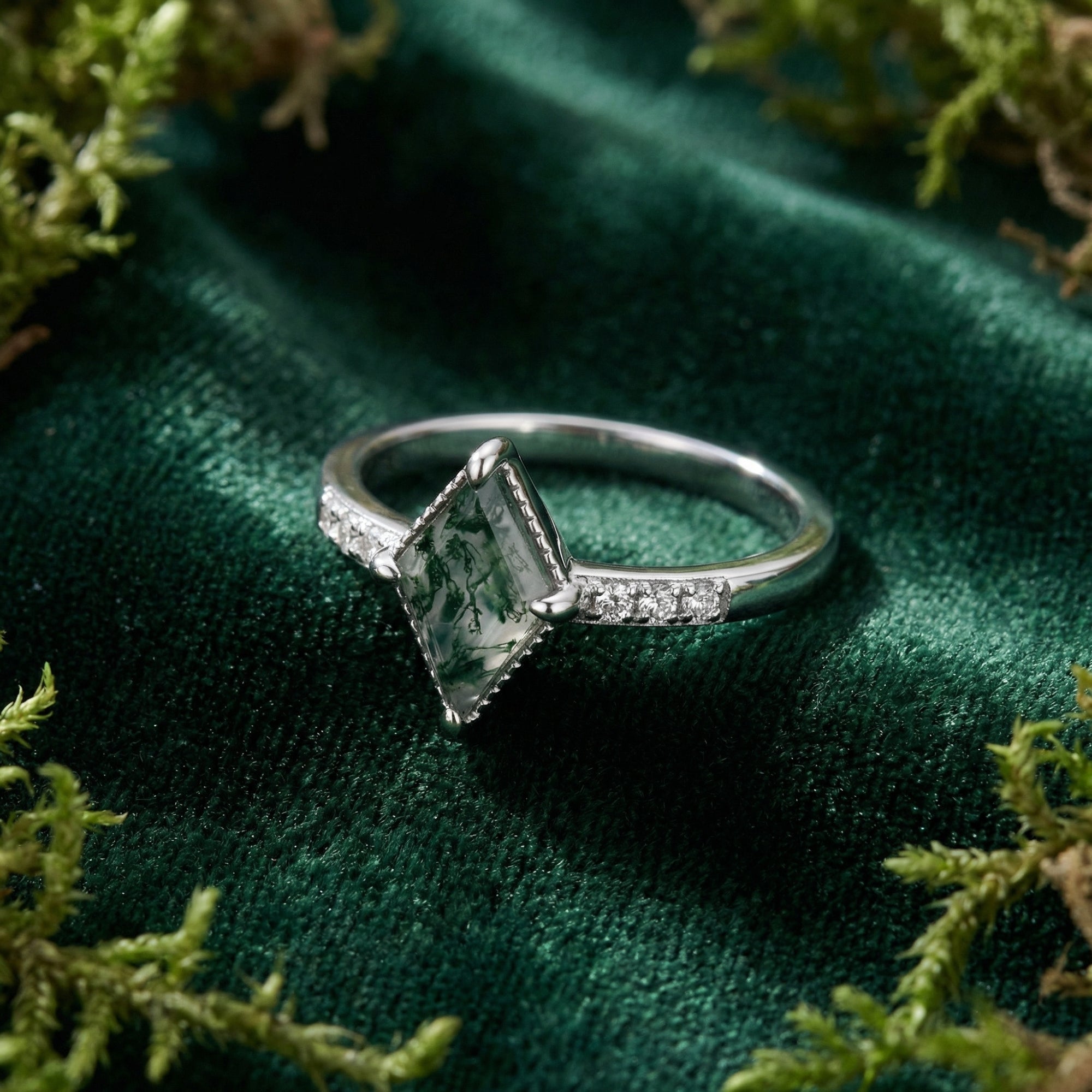 Kite cut natural moss agate ring in S925 sterling silver displayed on green velvet with decorative moss.