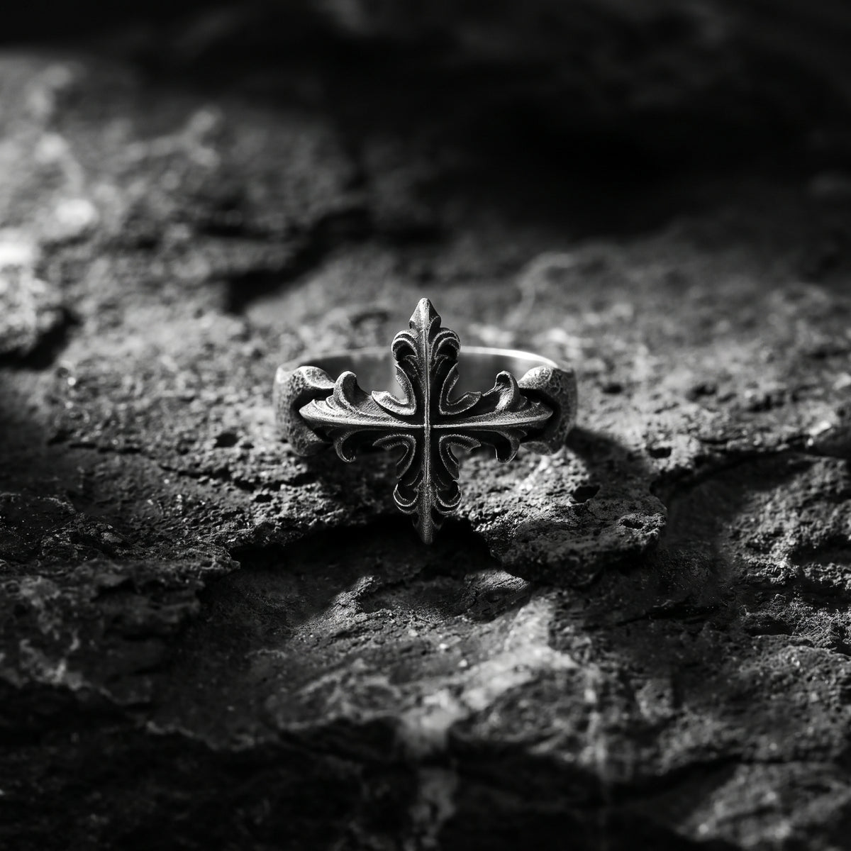 Front view of the silver open ring with a detailed Gothic cross centered on rough dark rock.
