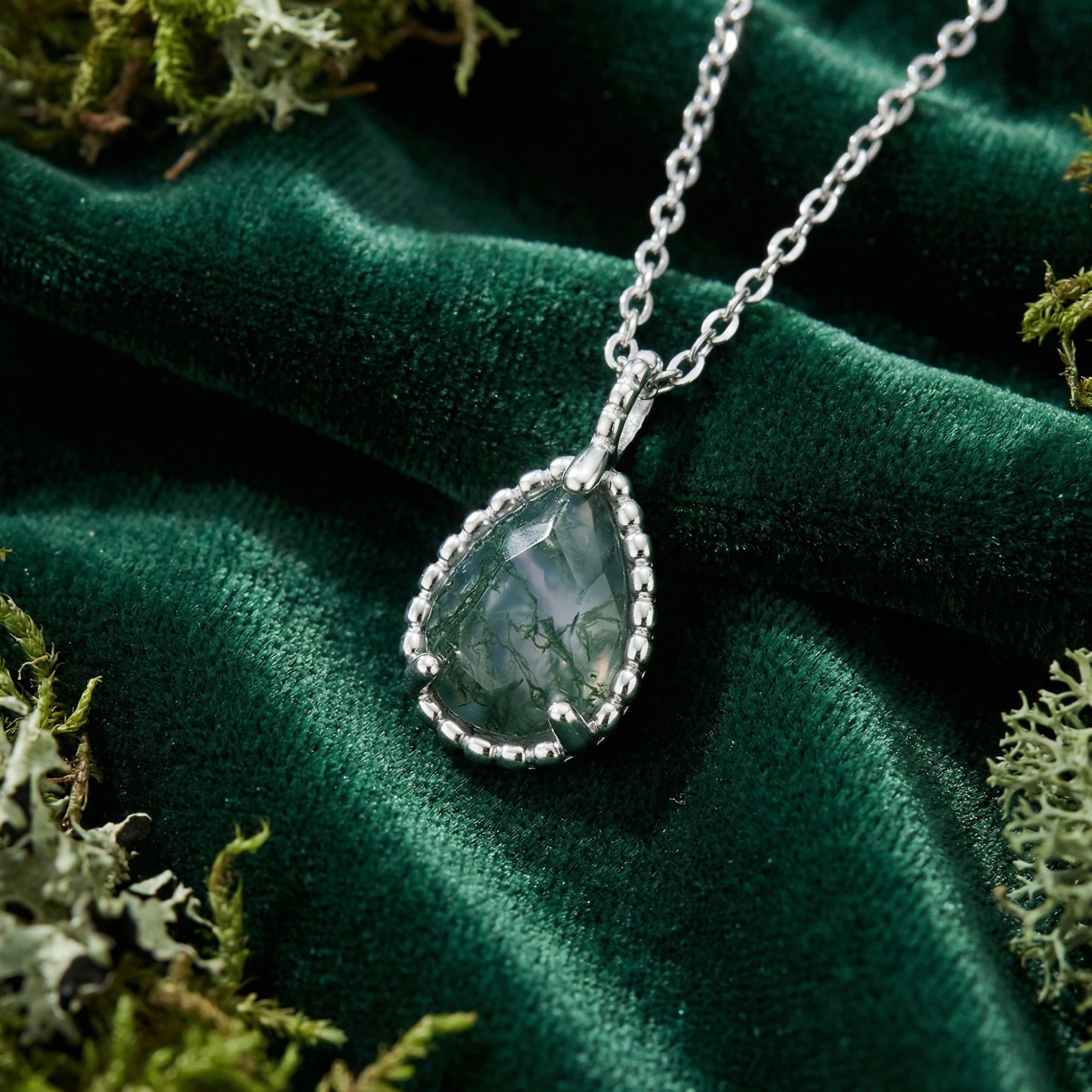 Teardrop moss agate basket weave pendant necklace in S925 sterling silver on green velvet with moss.
