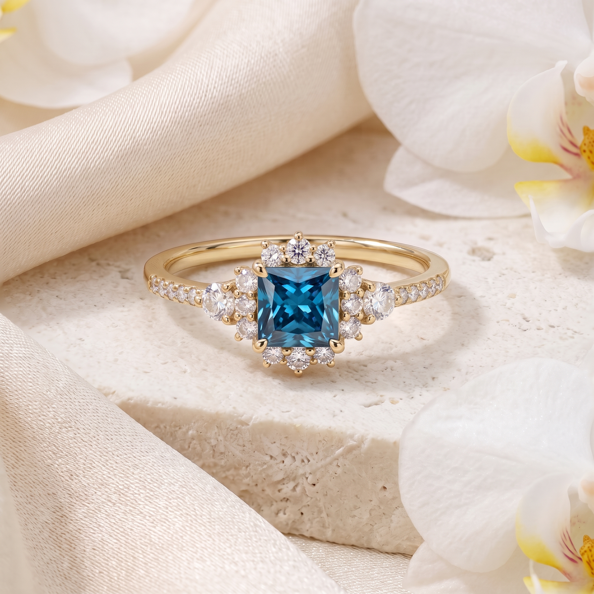 Yellow gold princess cut teal blue moissanite engagement ring with a diamond halo on a stone display.
