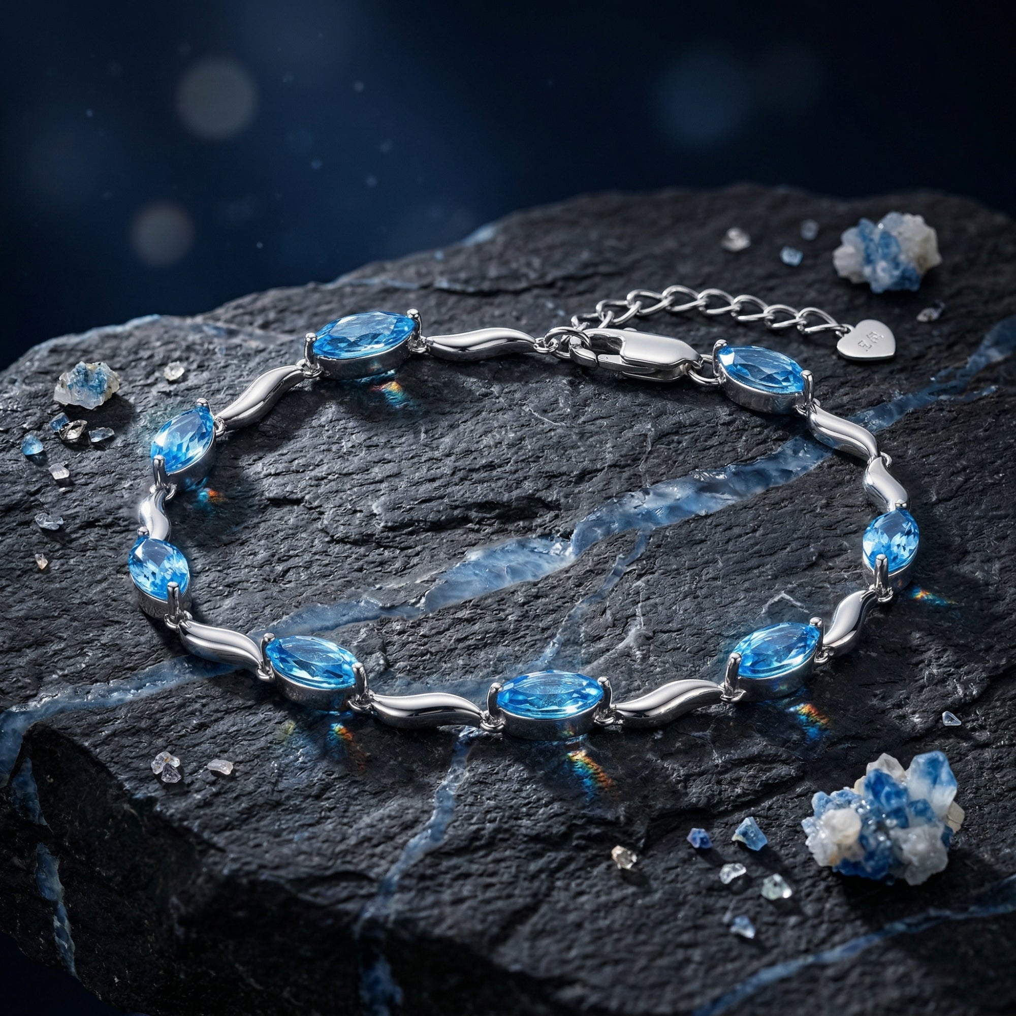 Marquise cut natural blue topaz bracelet in silver, displayed on a dark textured rock background.