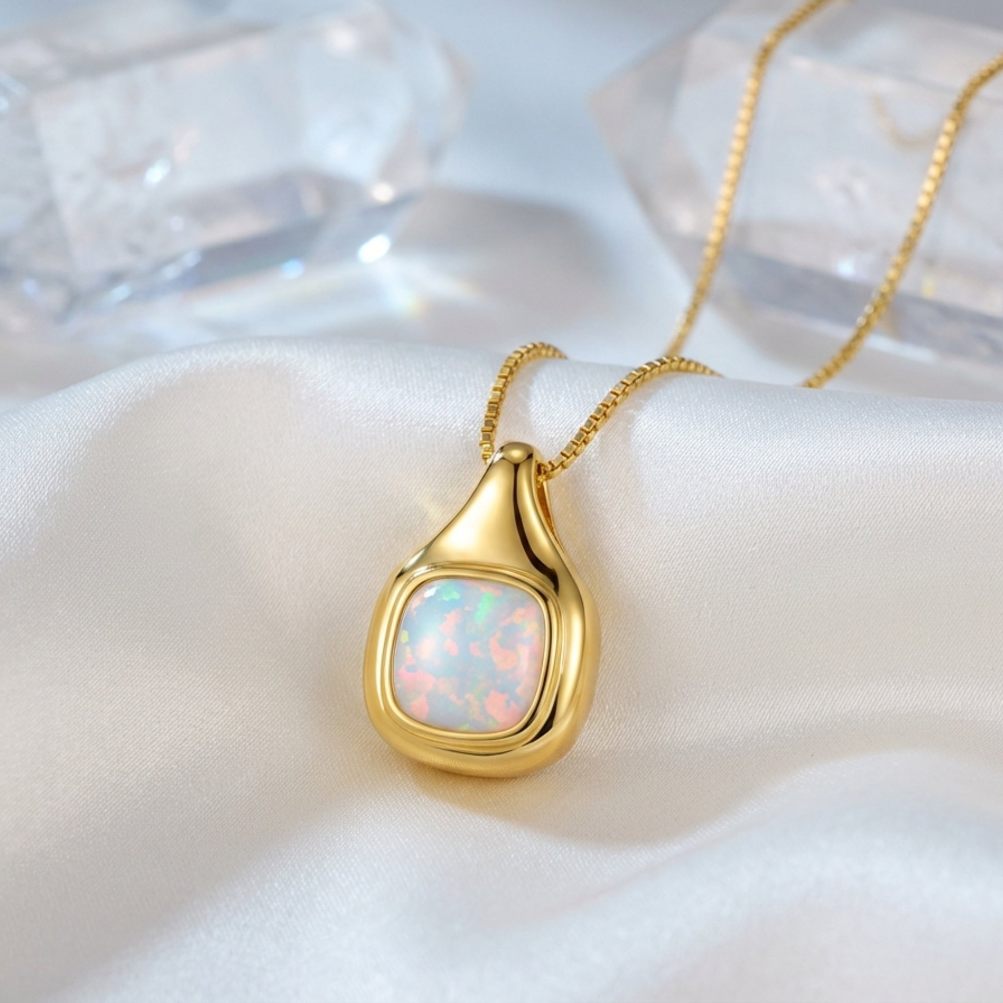 Gold vermeil cushion cut white opal pendant necklace styled on white silk with crystal points.