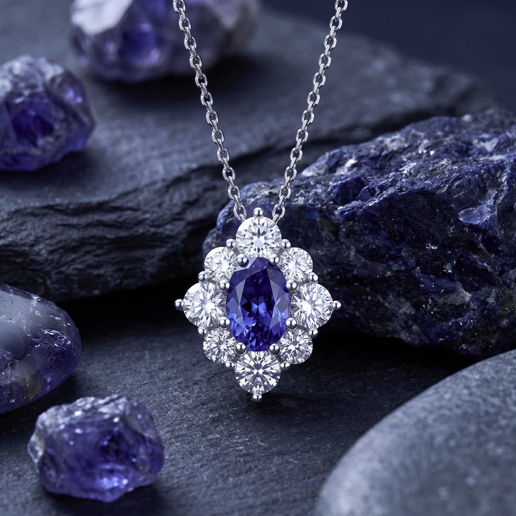 Oval natural tanzanite halo pendant in white gold on a silver chain, displayed with raw tanzanite stones.