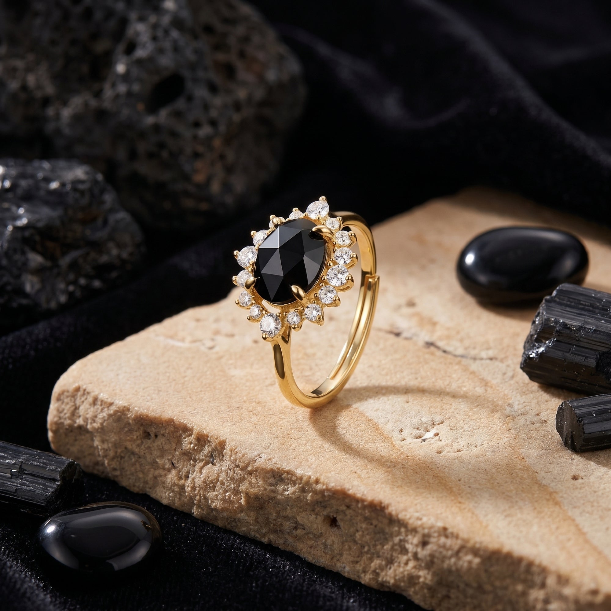 Angled view of the 18K gold plated Aurelius onyx ring with a clear stone halo on a natural rock background.