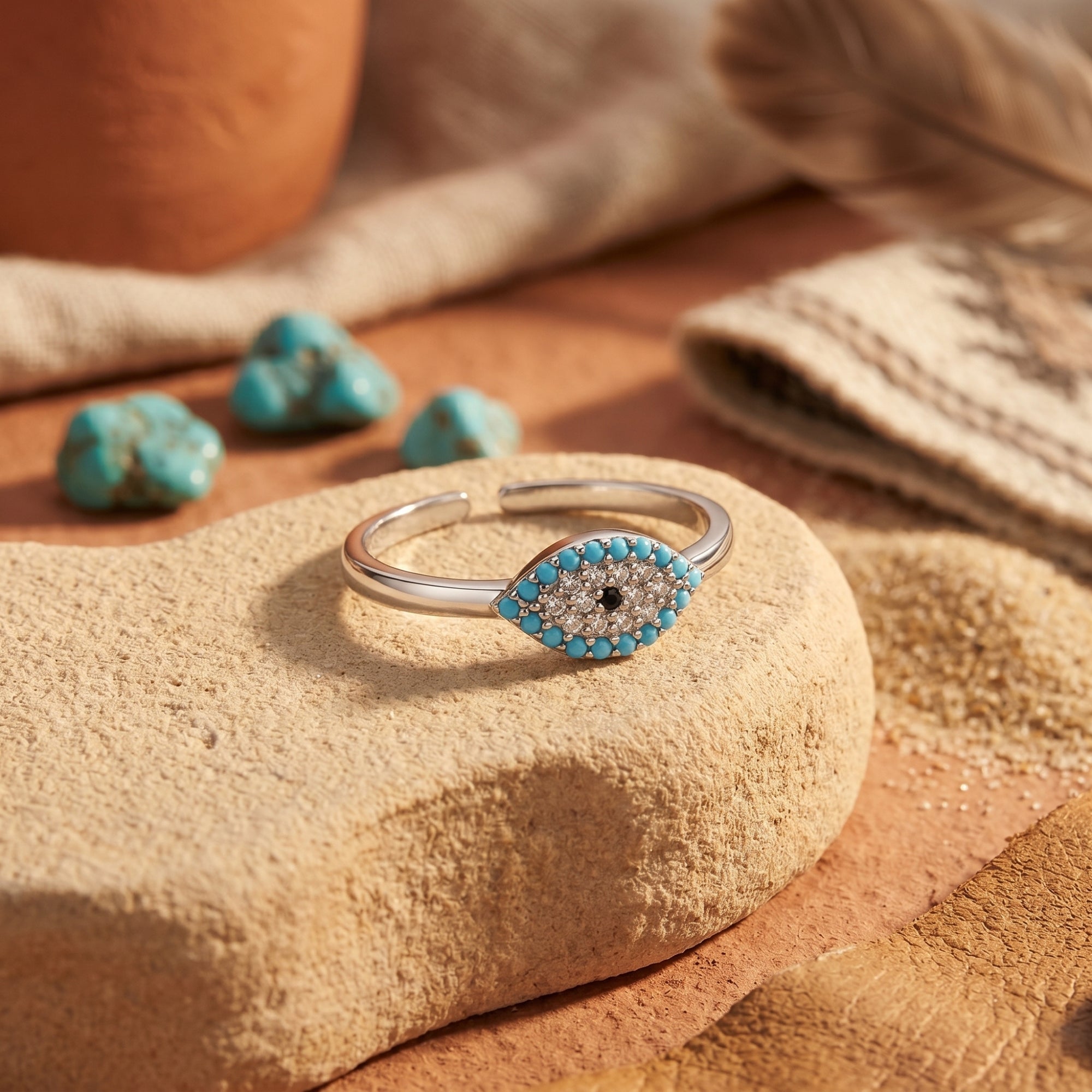 Silver evil eye ring with turquoise beads on a desert stone in a Southwestern-inspired lifestyle setting.