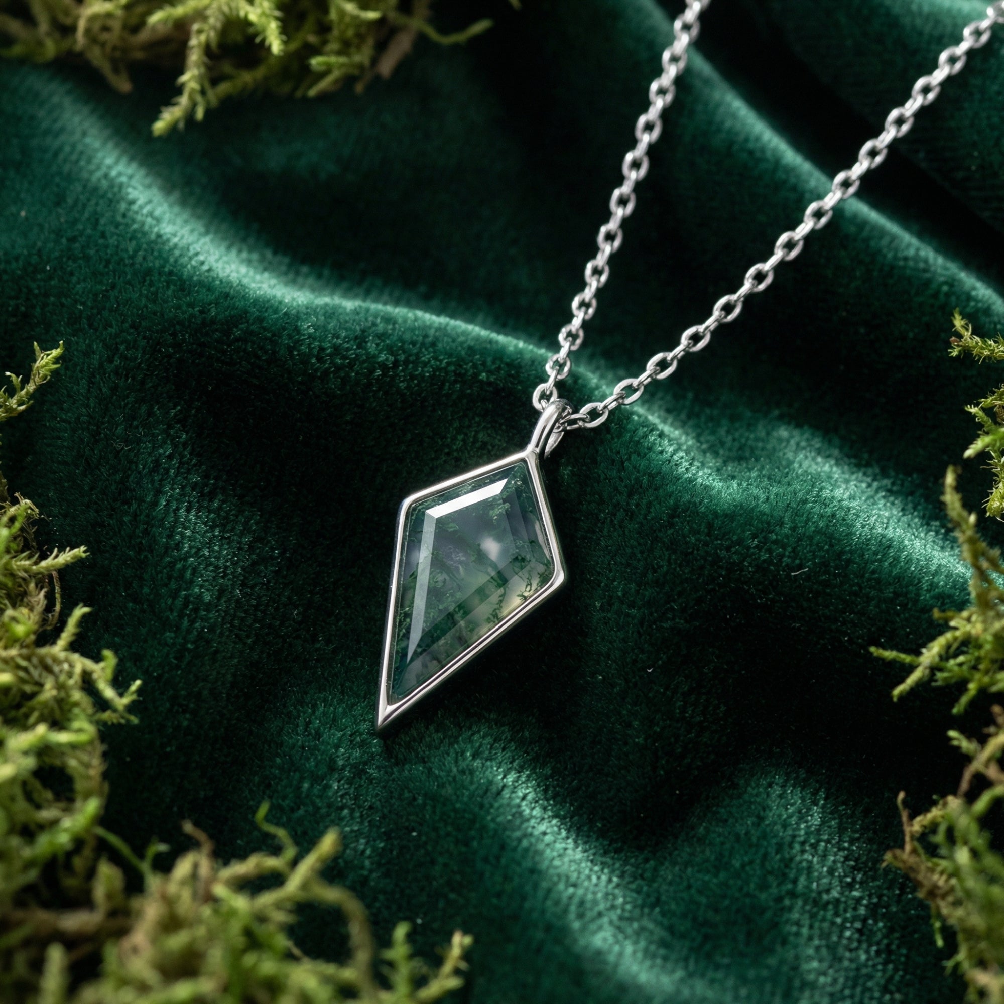 Kite cut moss agate pendant necklace in S925 sterling silver on green velvet with natural moss accents.