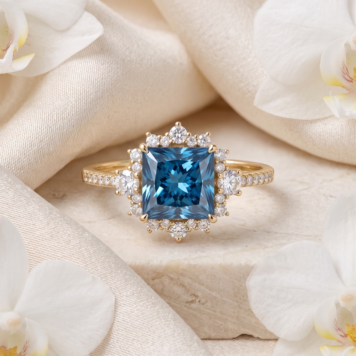 Front view of a yellow gold engagement ring featuring a princess cut London blue center stone with a vintage halo.