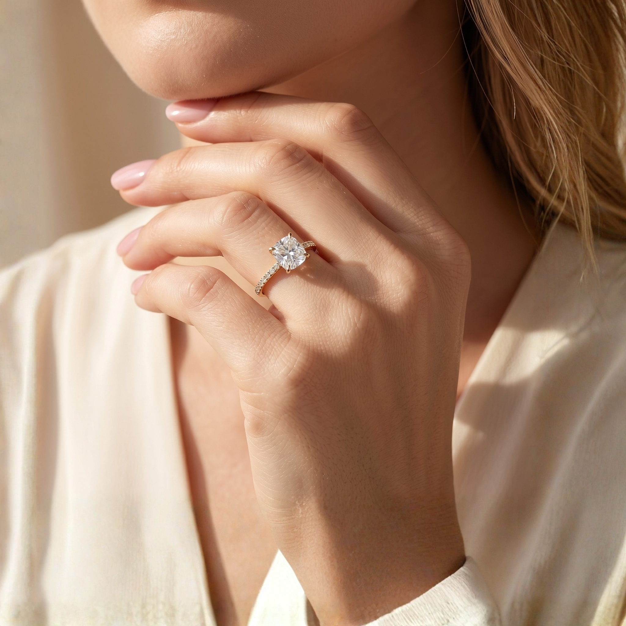 A model showcasing a cushion-cut moissanite engagement ring in yellow gold on her finger.