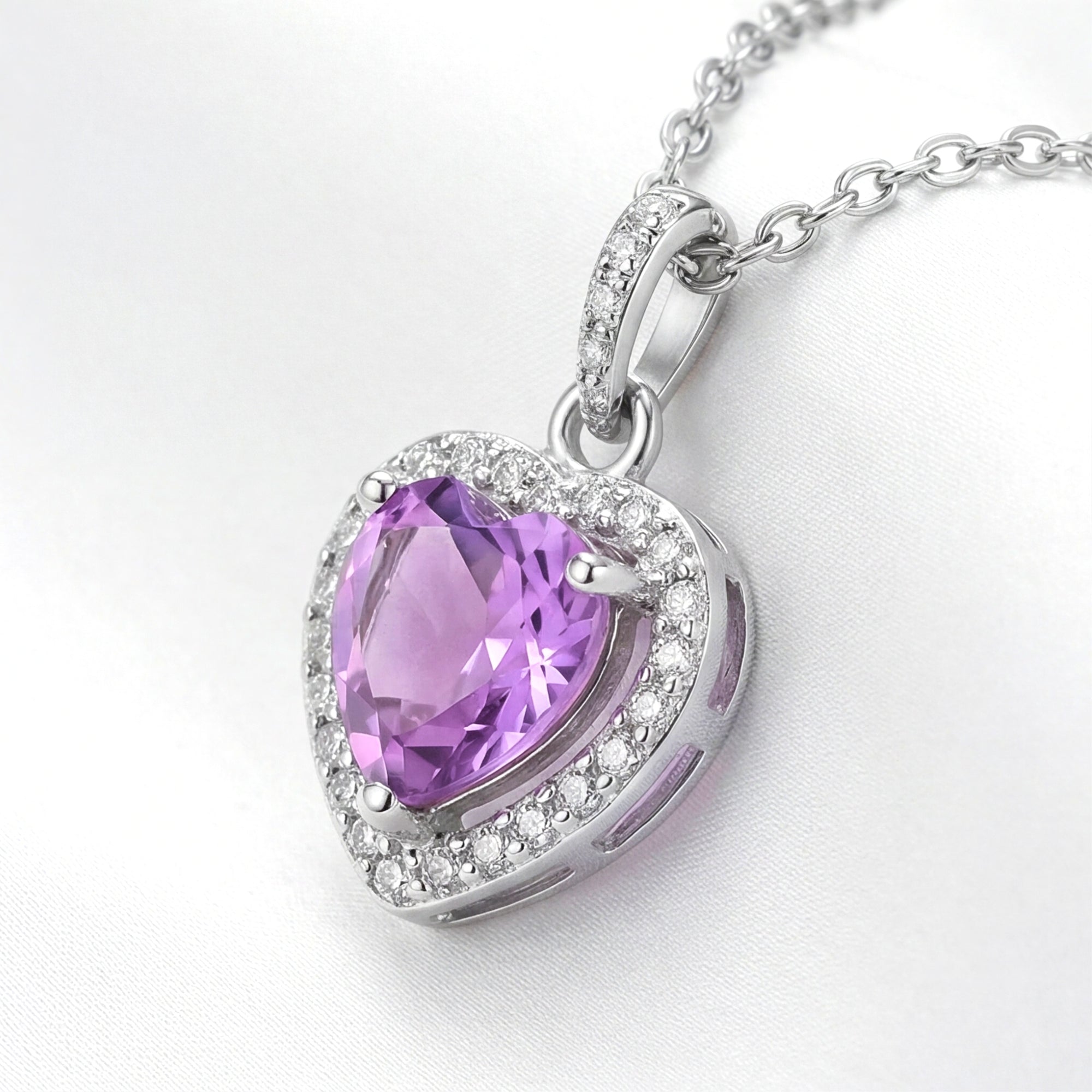 Side view of a heart-cut simulated amethyst pendant in sterling silver with a pavé halo and stone-set bail.