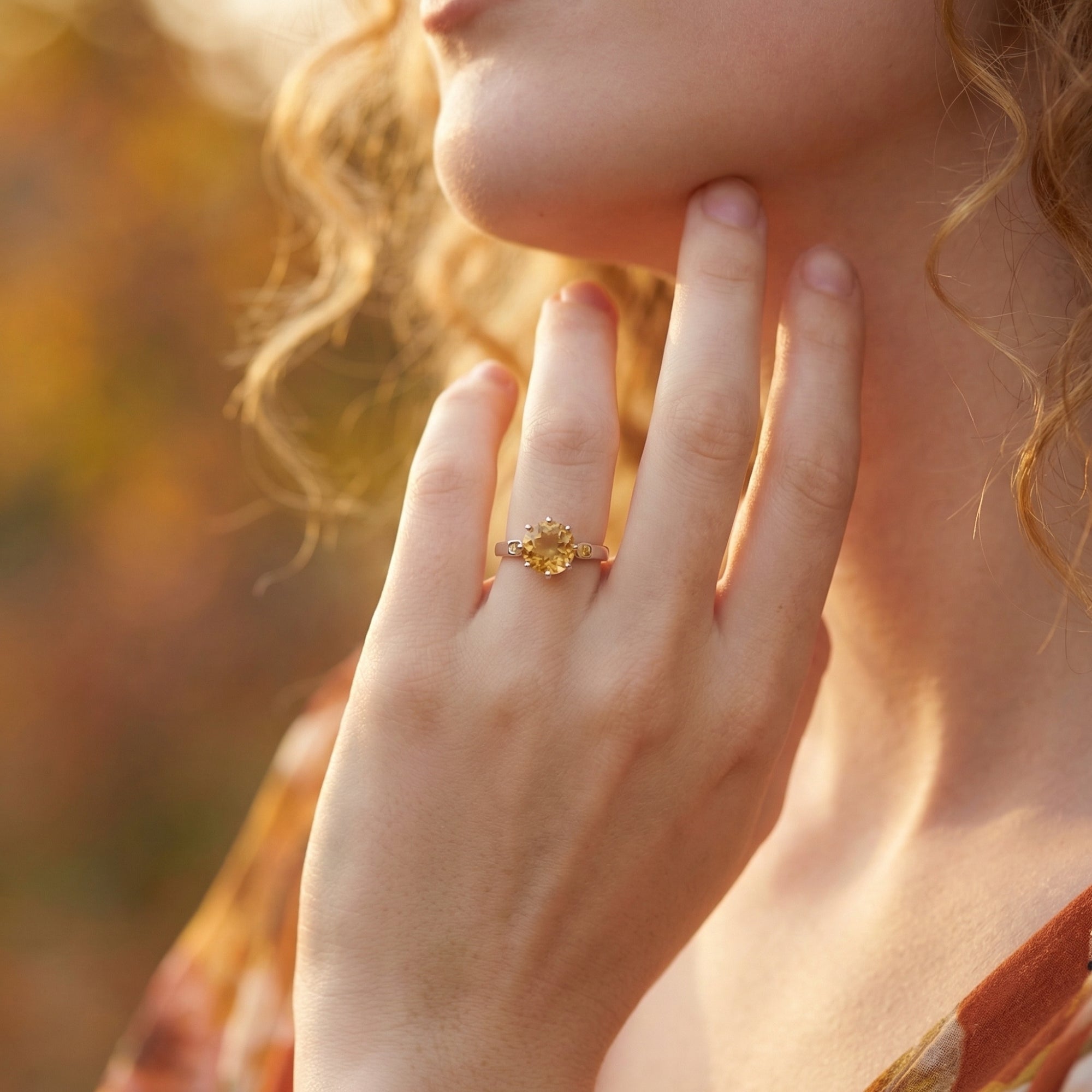 Model wearing the round cut natural citrine ring in sterling silver on her finger during golden hour.