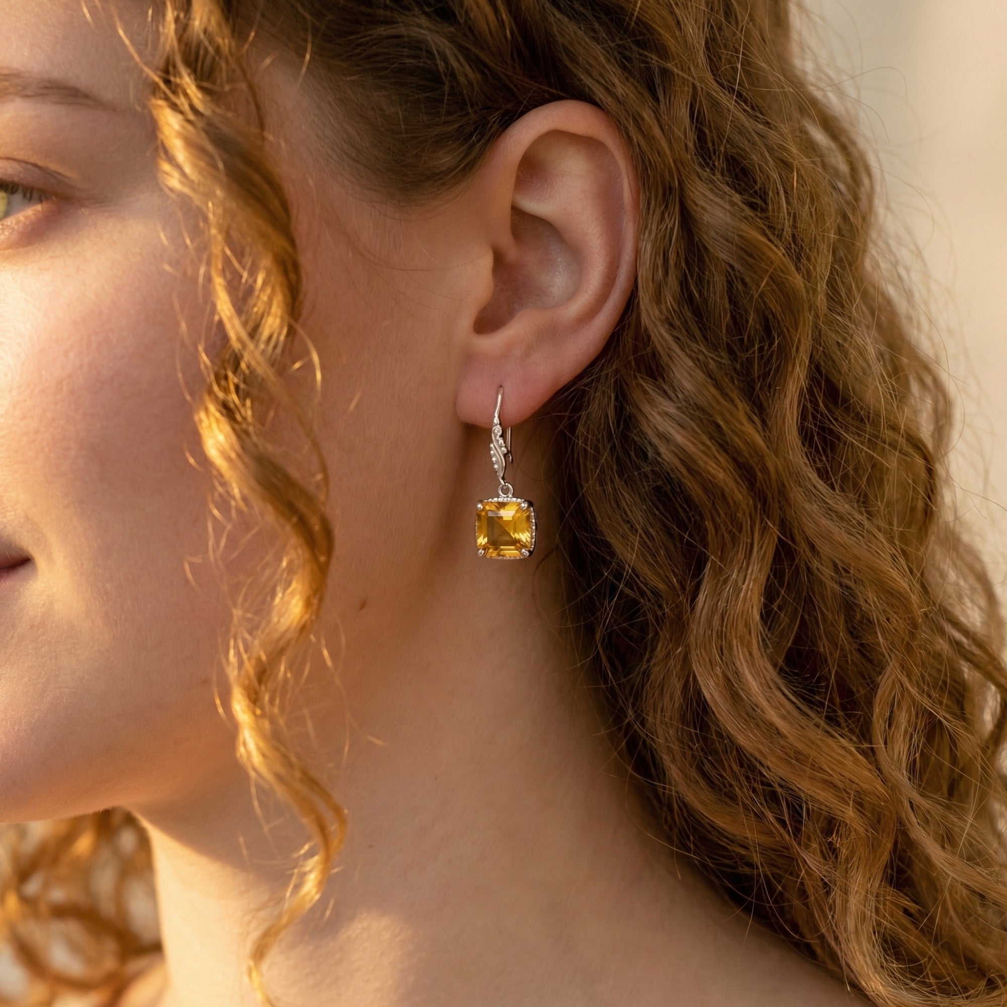 Woman wearing a square cut natural citrine drop earring in silver, showcasing the November birthstone jewelry.
