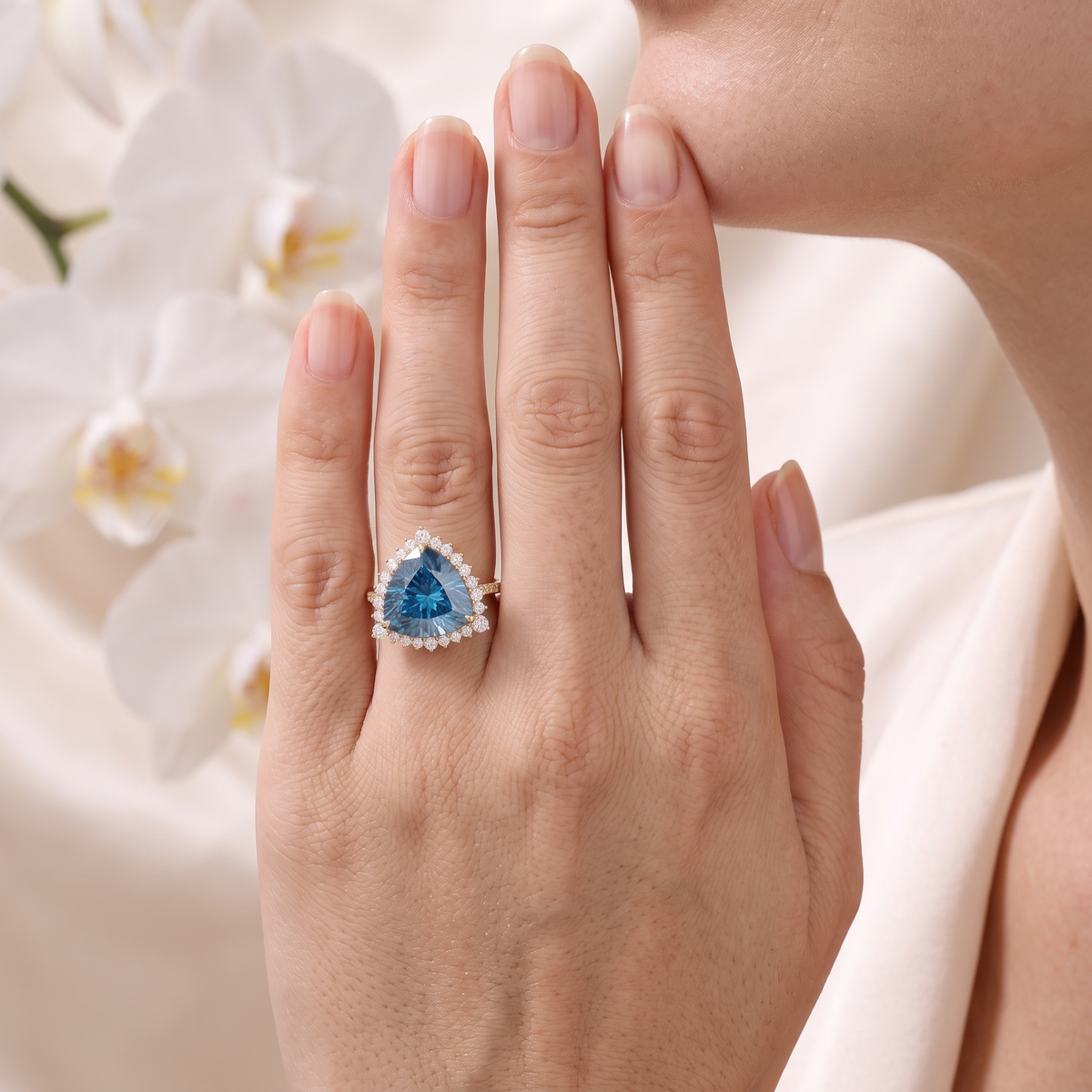 Trillion-cut blue moissanite halo ring in rose gold worn on a woman's hand.