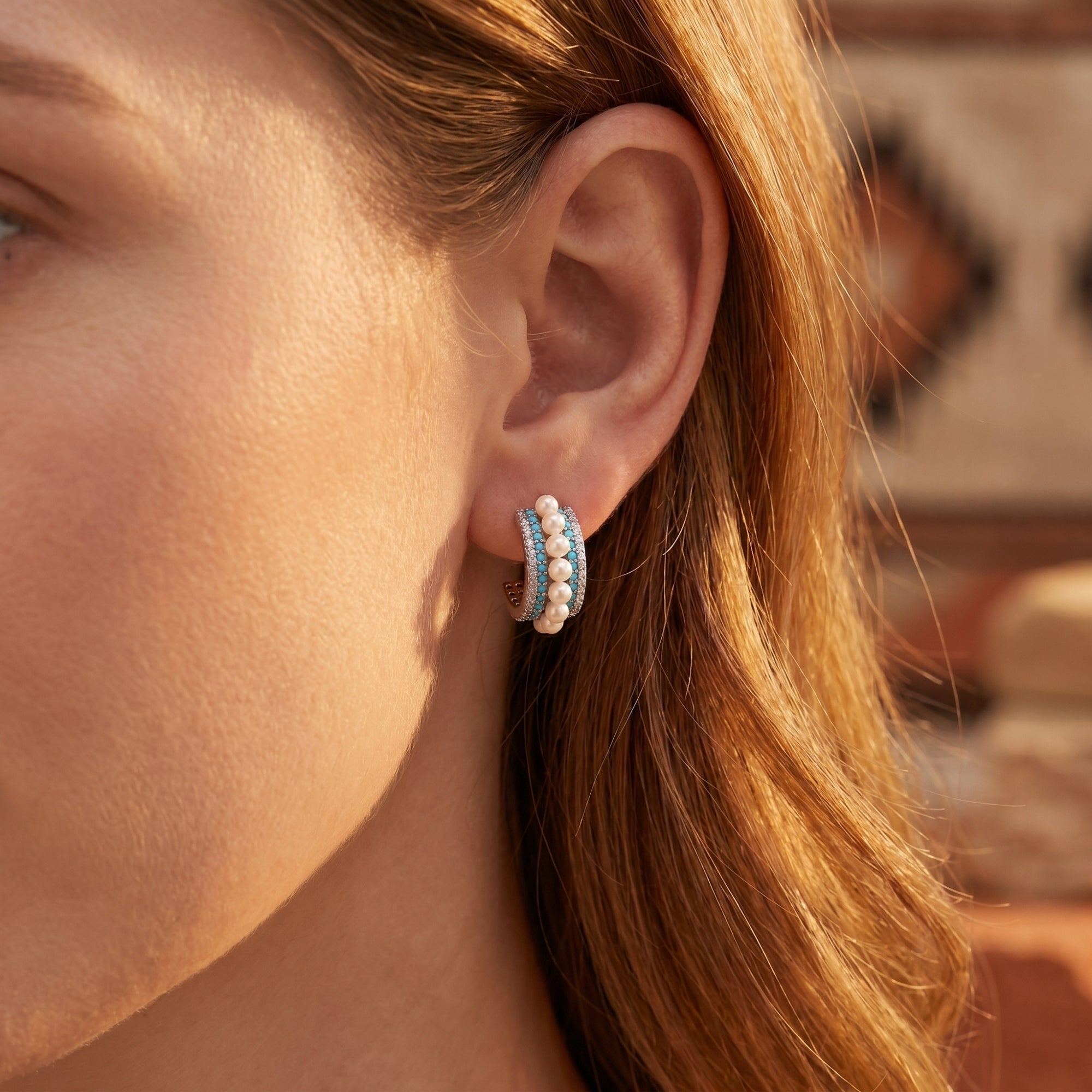 Close-up of a model wearing a silver turquoise and pearl C-hoop earring.