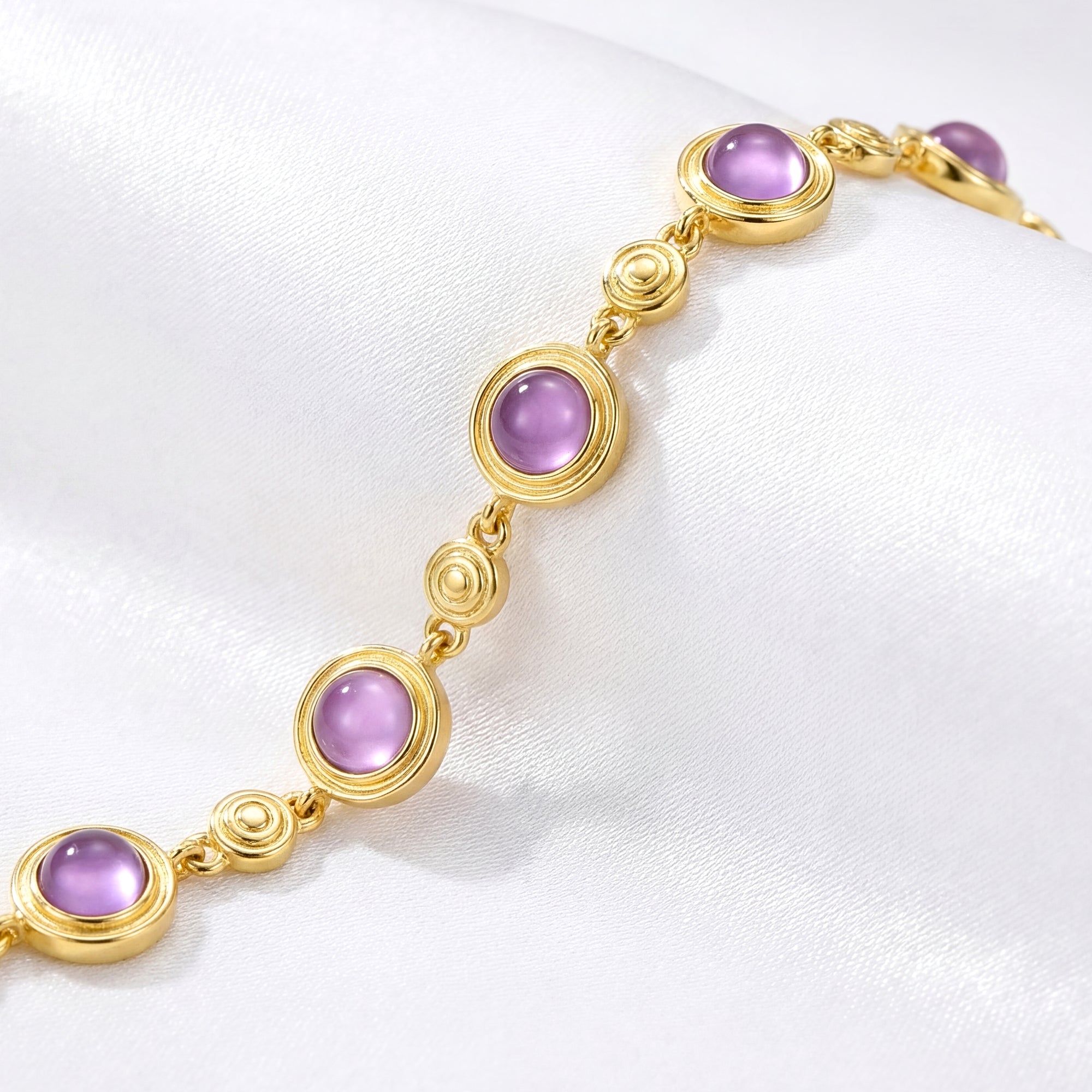 Close-up of round cut simulated amethyst stones and decorative gold vermeil links on the Evangeline bracelet.