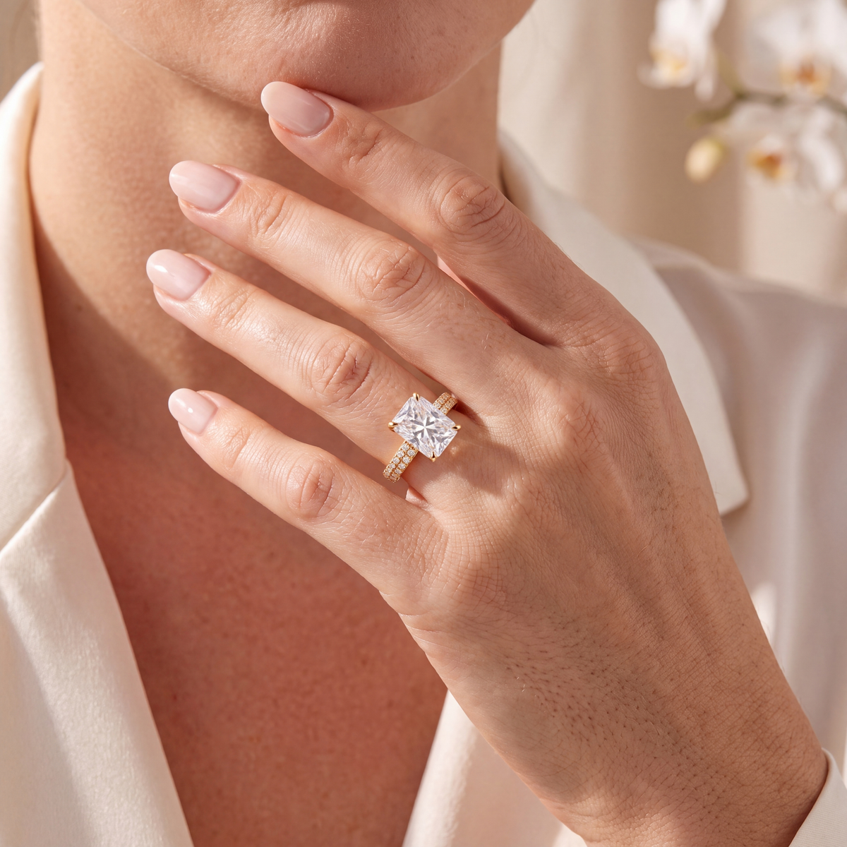 Close-up of a hand wearing a yellow gold radiant-cut moissanite ring.