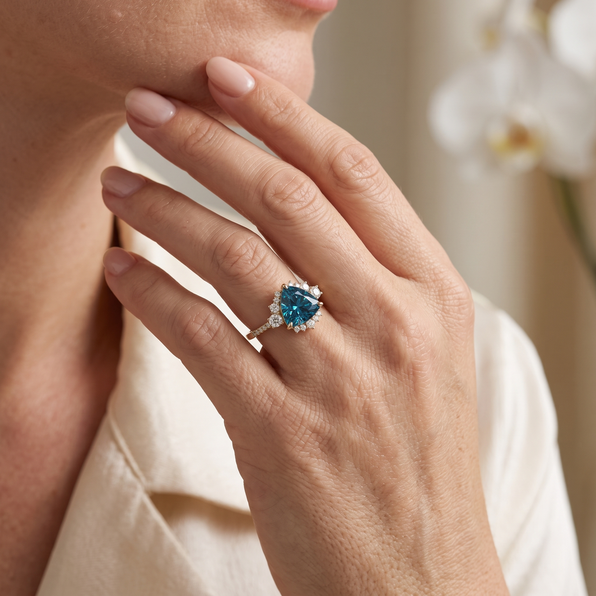 Close-up of a model wearing a trillion-cut blue moissanite halo ring in rose gold.