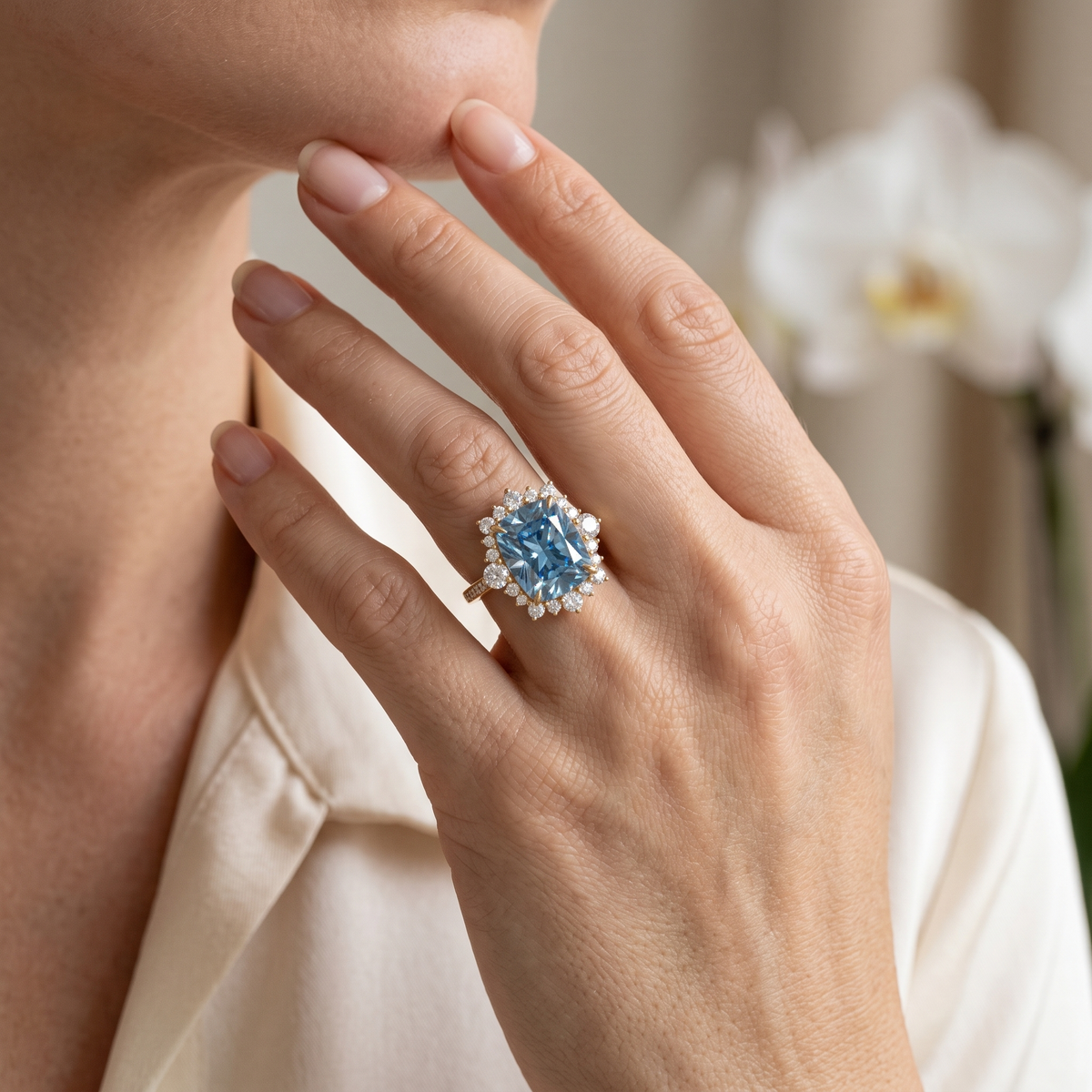 Close-up lifestyle shot of a hand wearing a yellow gold cushion-cut blue moissanite ring.