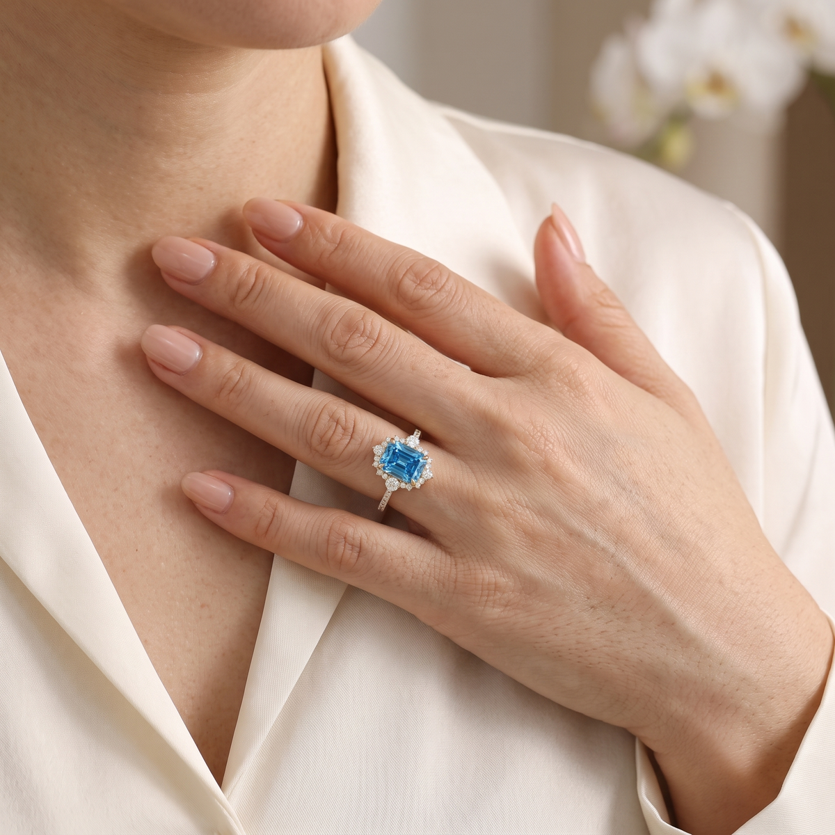 Rose gold emerald cut blue moissanite halo ring worn on woman's hand.