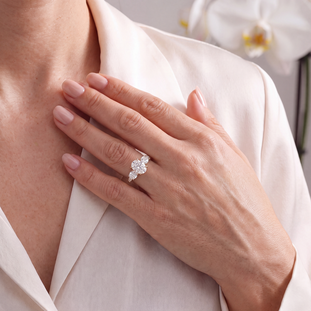 Model wearing a yellow gold three-stone oval moissanite ring on her finger.
