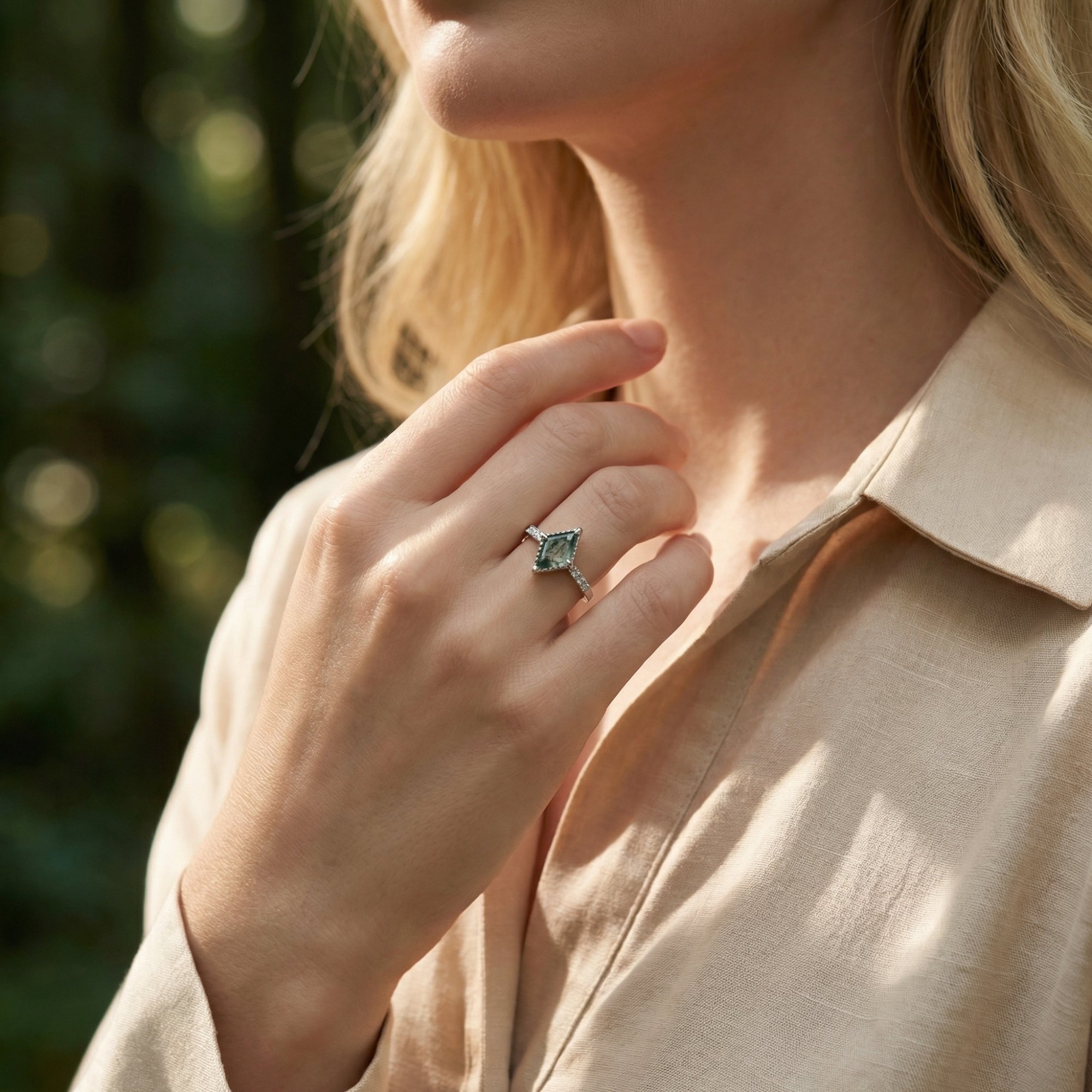 Model wearing a kite cut natural moss agate ring in sterling silver on her finger in natural outdoor light.