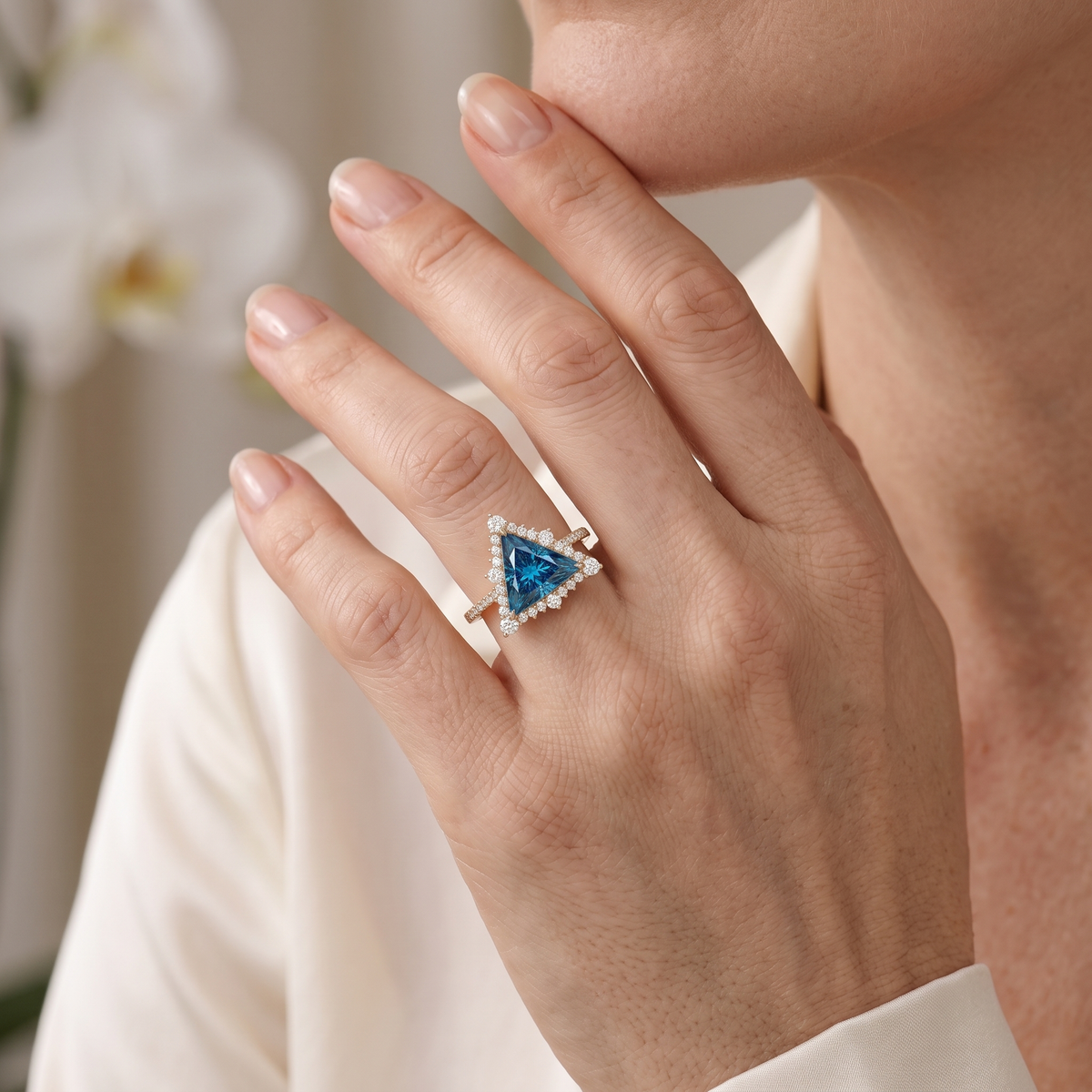 Close-up of a rose gold trillion-cut blue moissanite ring worn on a woman's hand