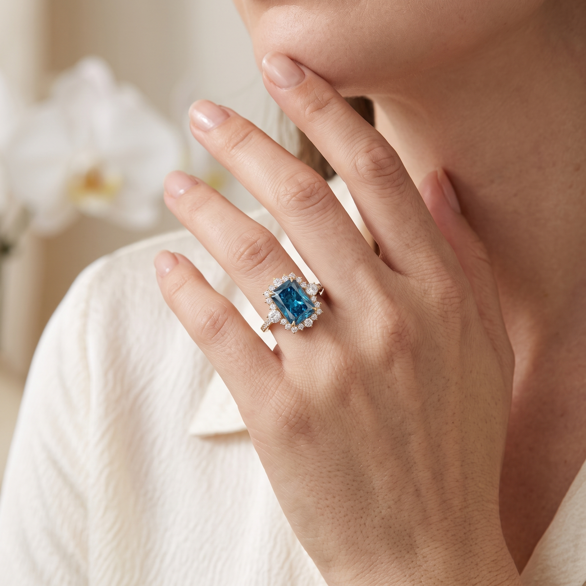 Model wearing a blue radiant cut moissanite halo ring in rose gold.