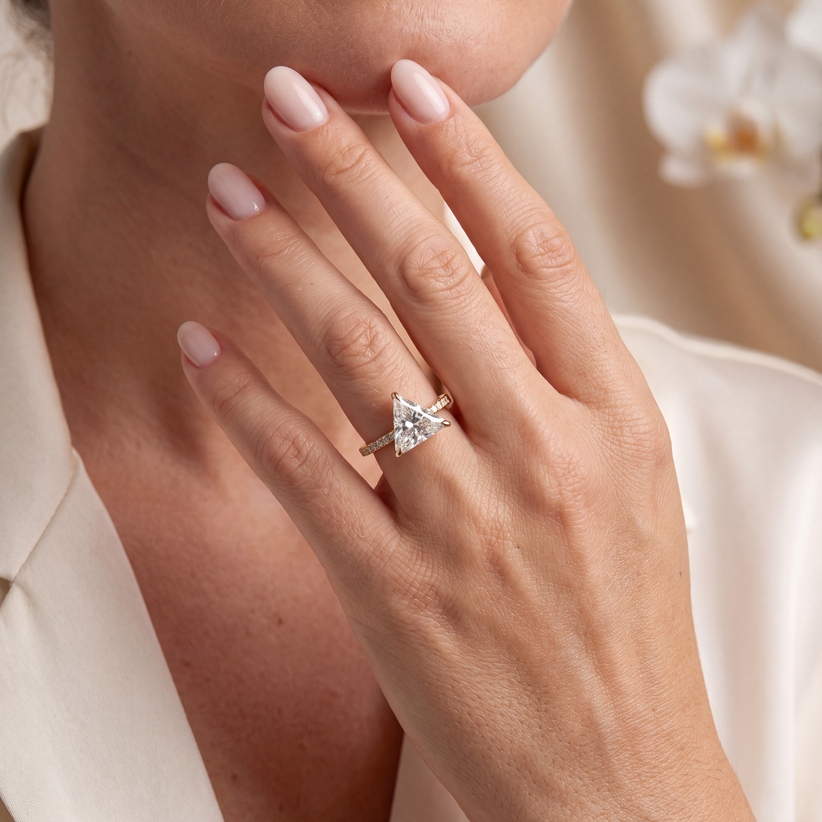 Trillion cut moissanite engagement ring in yellow gold worn on a woman's hand.