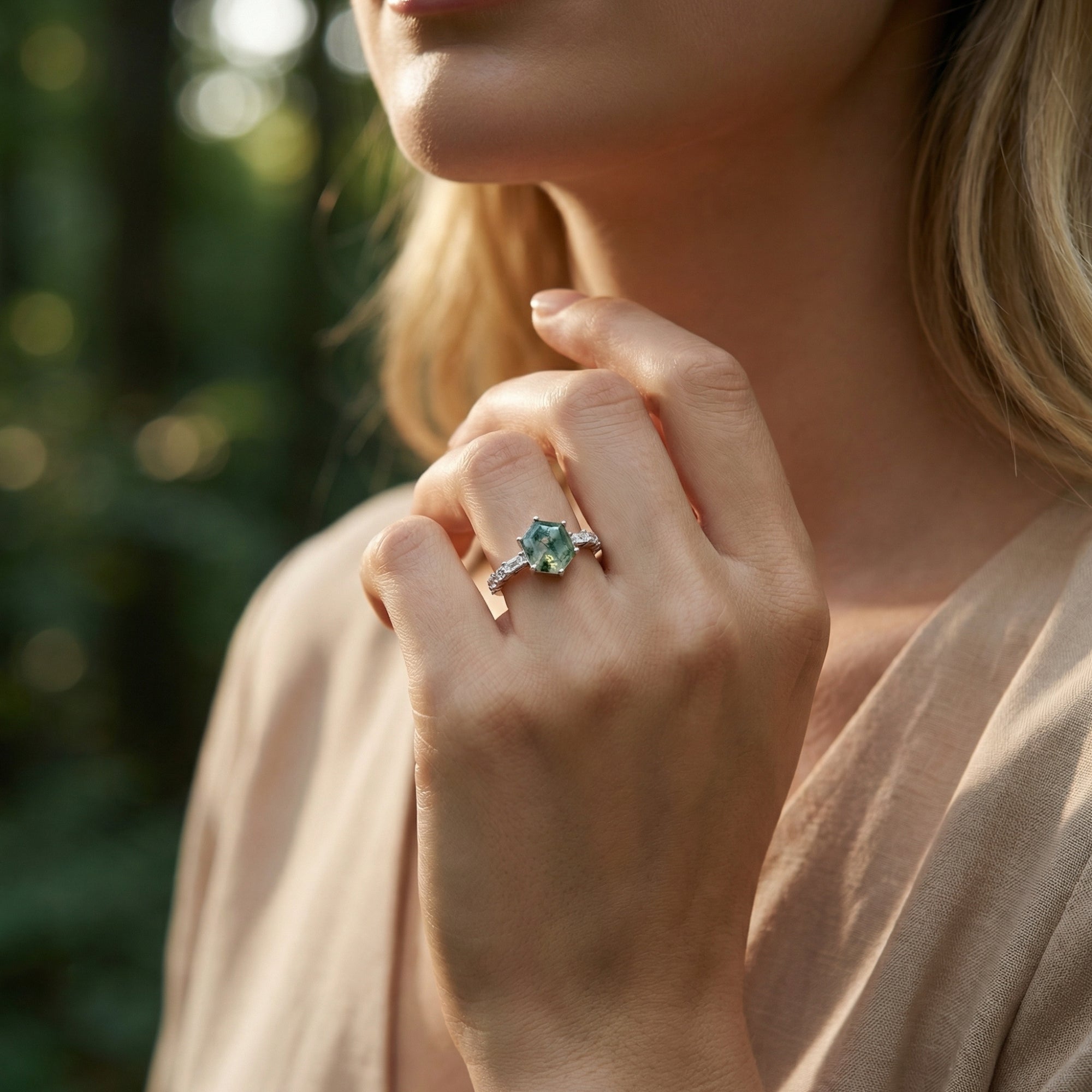 Model wearing a hexagonal moss agate sterling silver ring on her finger in a natural outdoor setting.