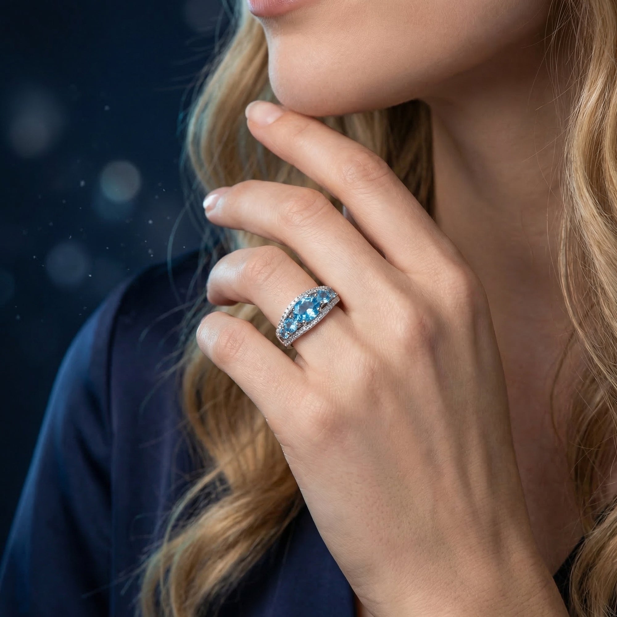 Sterling silver ring with an oval Swiss blue topaz worn on a woman's hand.