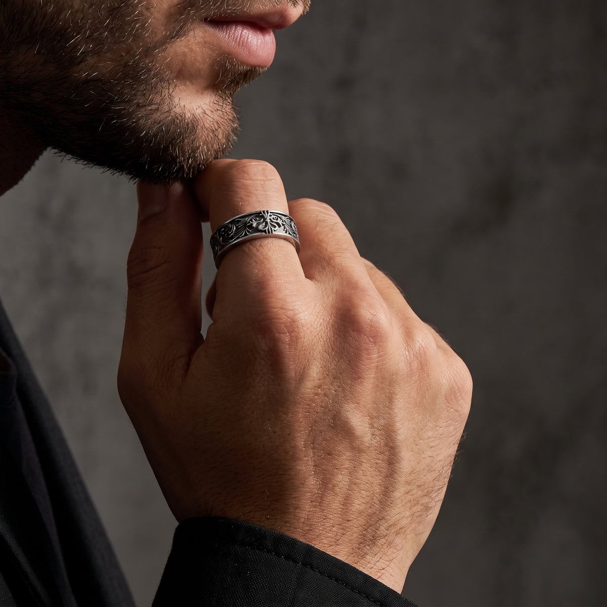 Close-up of a man touching his chin while wearing the oxidized silver filigree ring on his index finger.