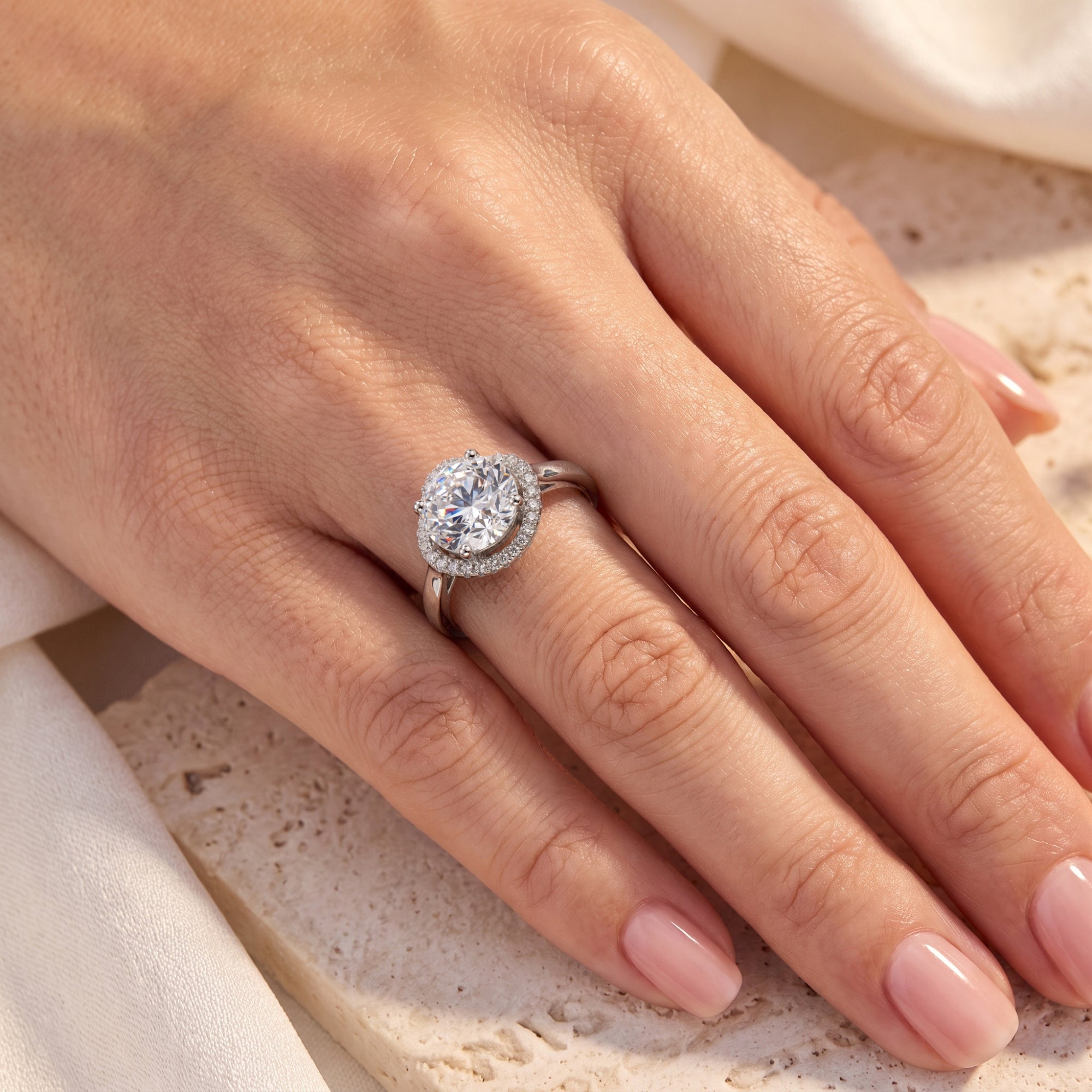 Sterling silver round halo simulated diamond ring worn on a woman's finger.