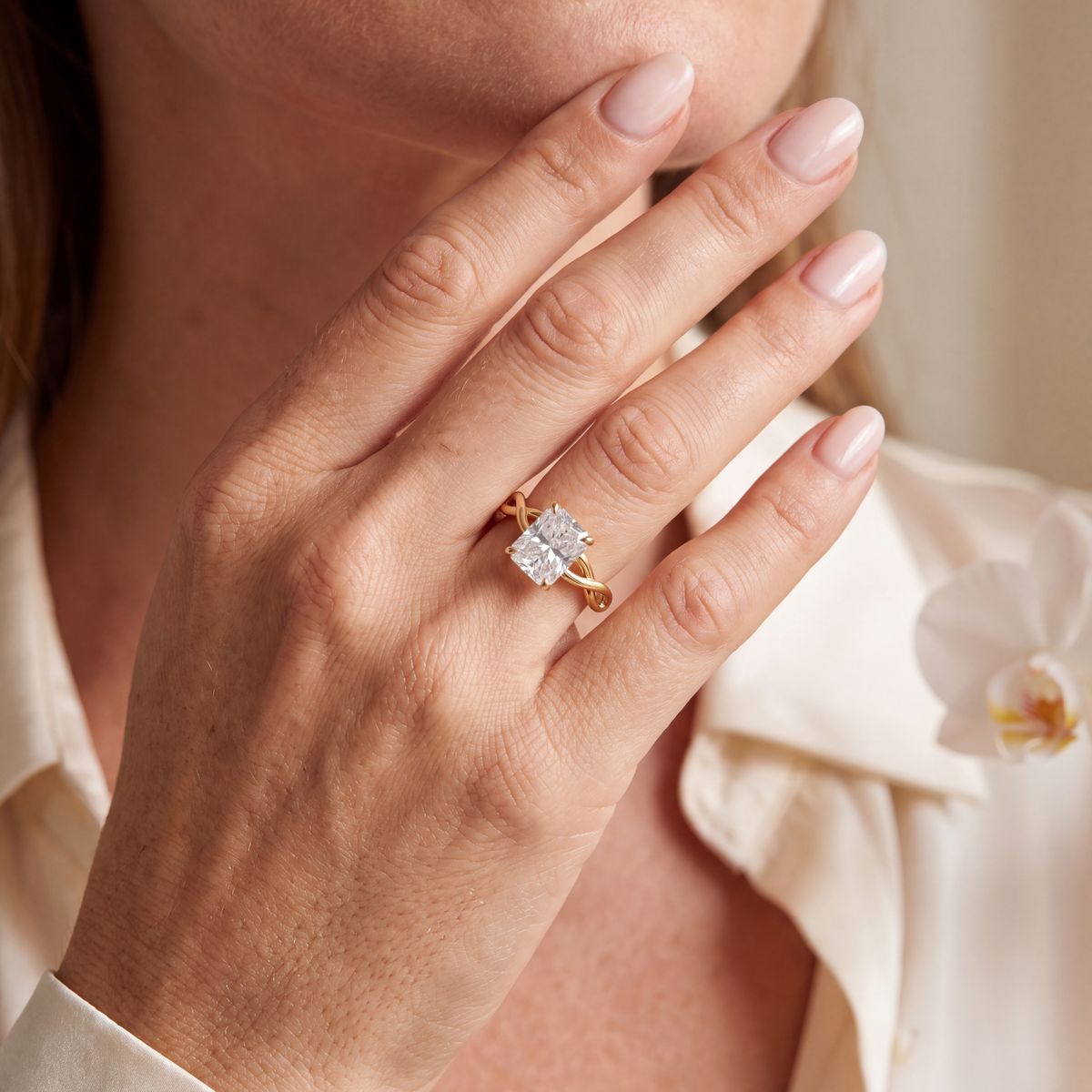 Radiant cut moissanite engagement ring in yellow gold worn on a hand.