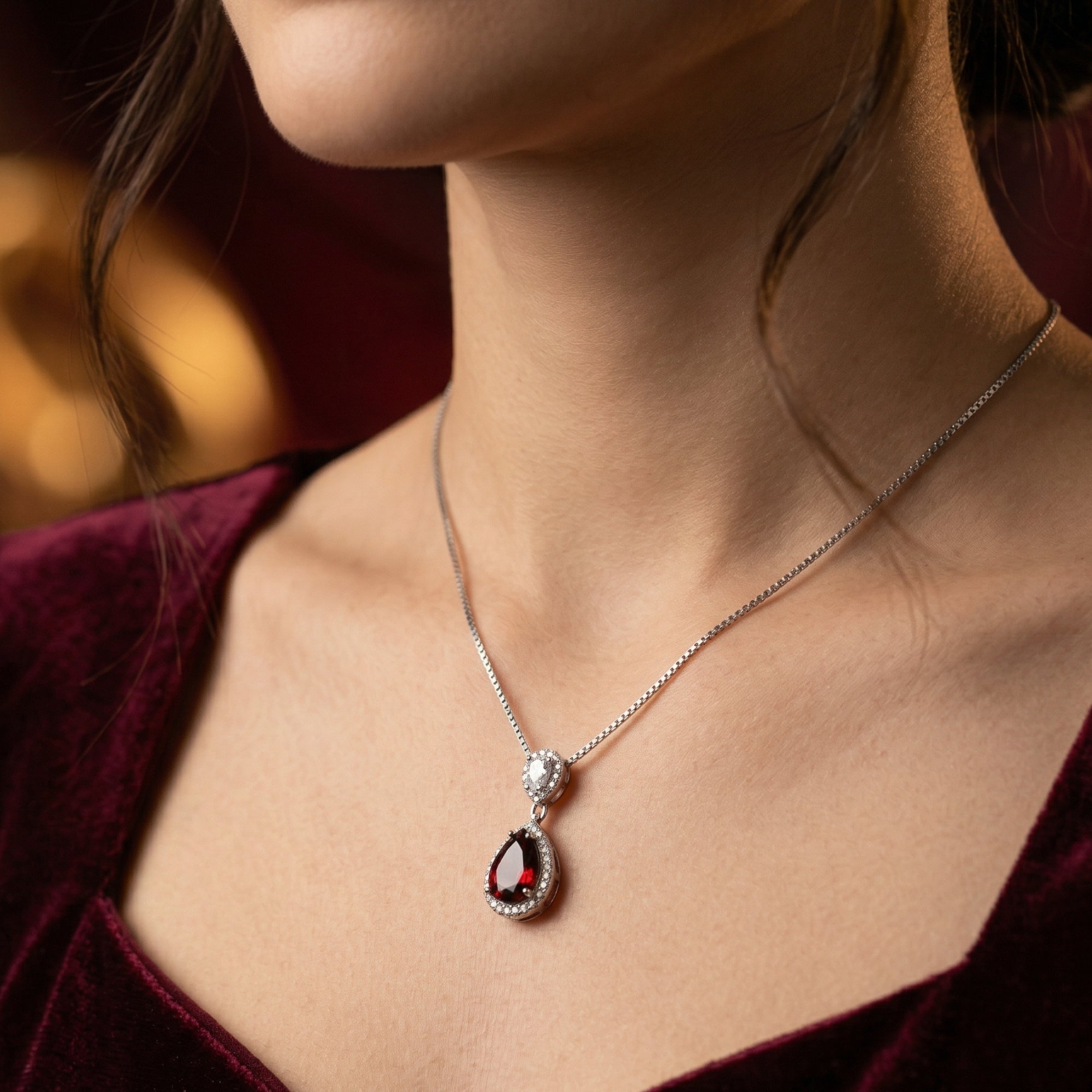 Side view of the Ilaria pear cut garnet necklace in silver worn by a woman on a delicate box chain.