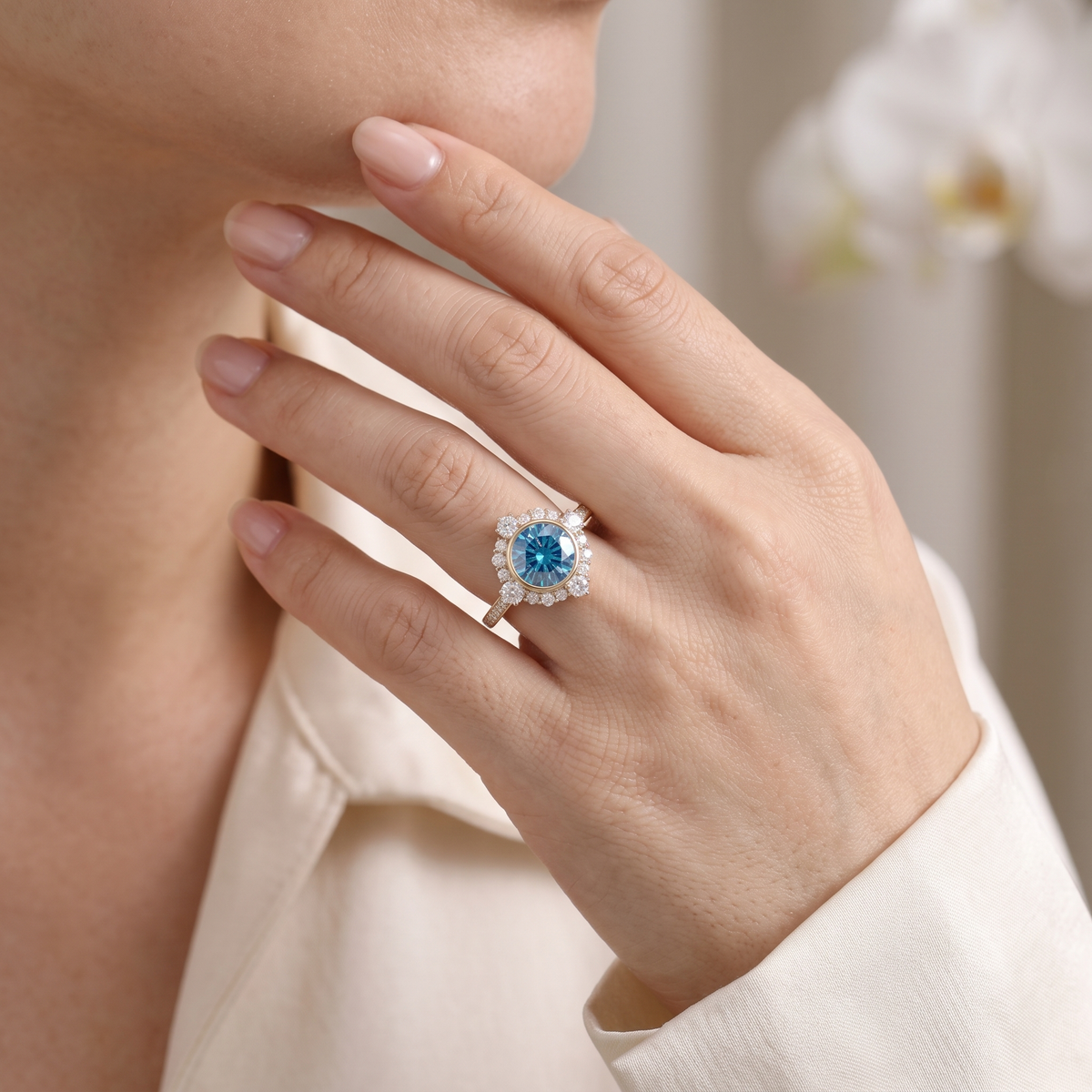 Close-up of a hand wearing a round blue moissanite vintage halo engagement ring in rose gold.