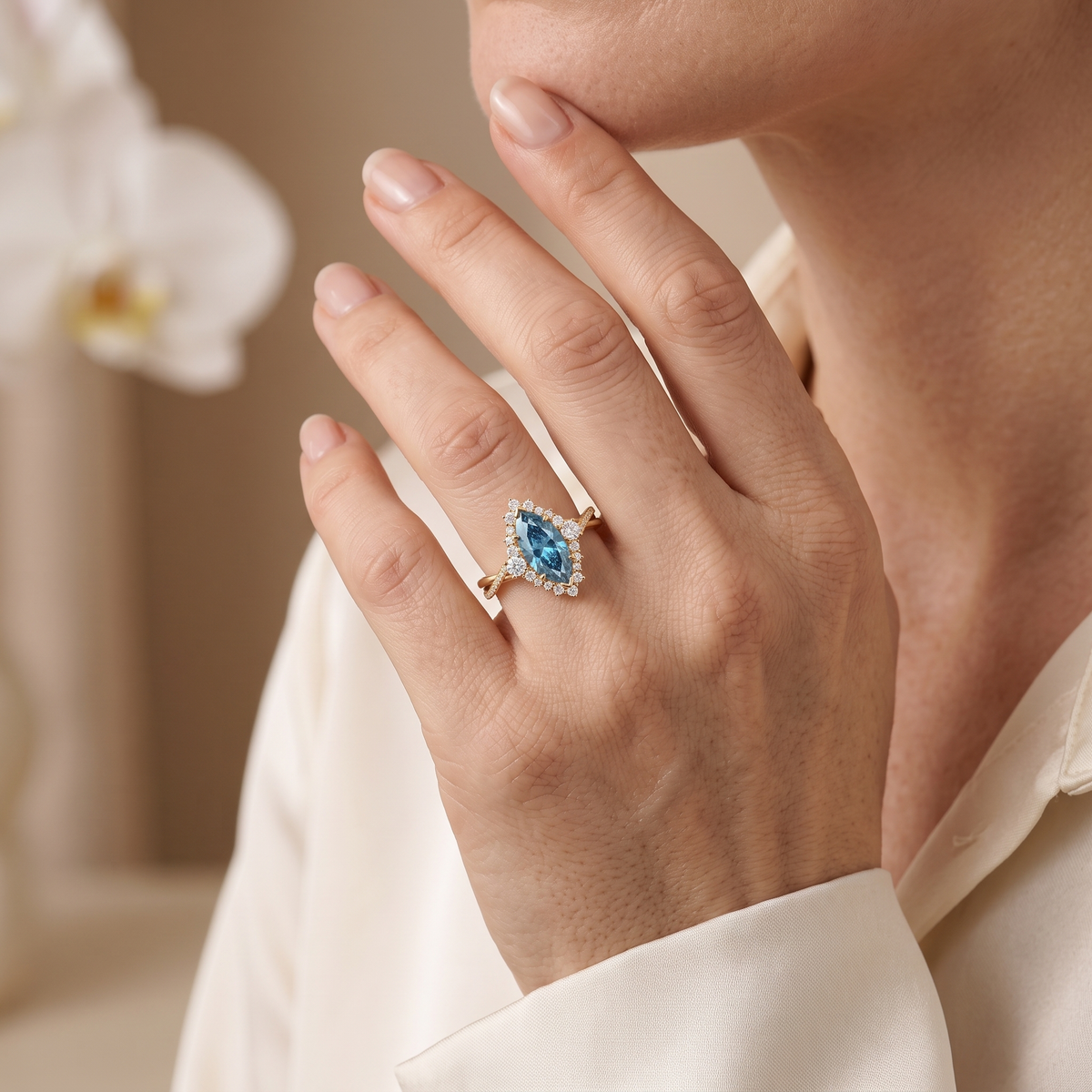 Lifestyle photo of a model wearing a yellow gold blue marquise moissanite ring with a halo and twisted band on her finger.