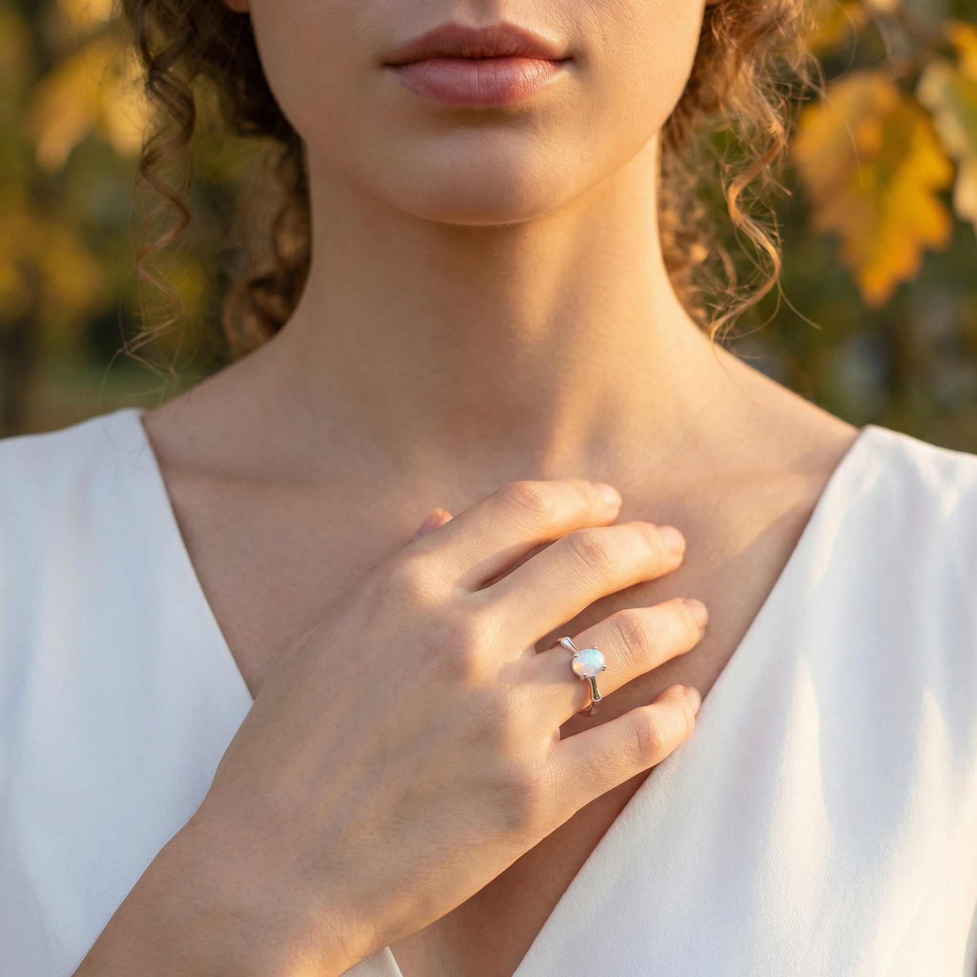 Model wearing the Guinevere oval opal statement ring in sterling silver on her hand against a white dress.