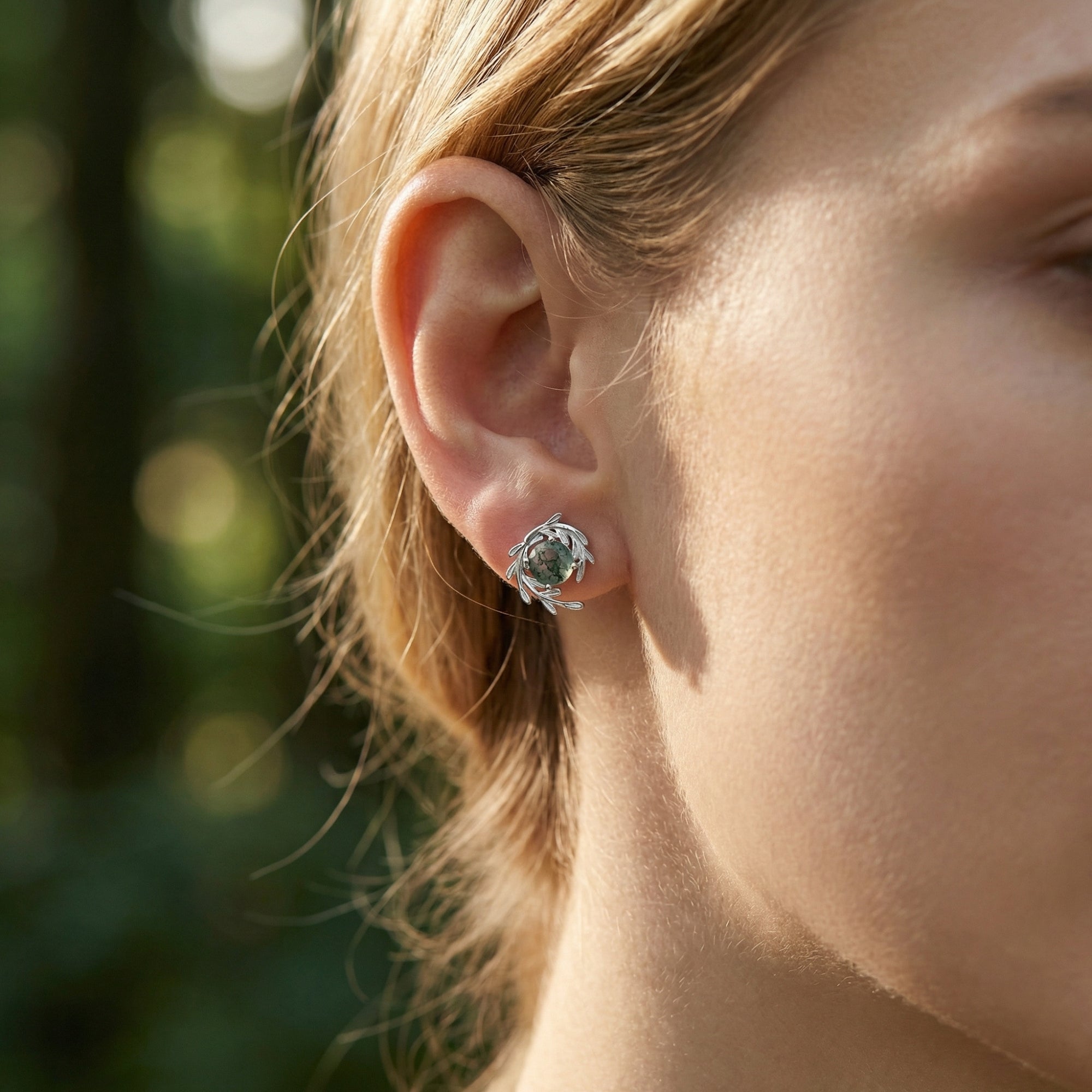 Model wearing a silver vine wrap stud earring with a natural green moss agate stone.