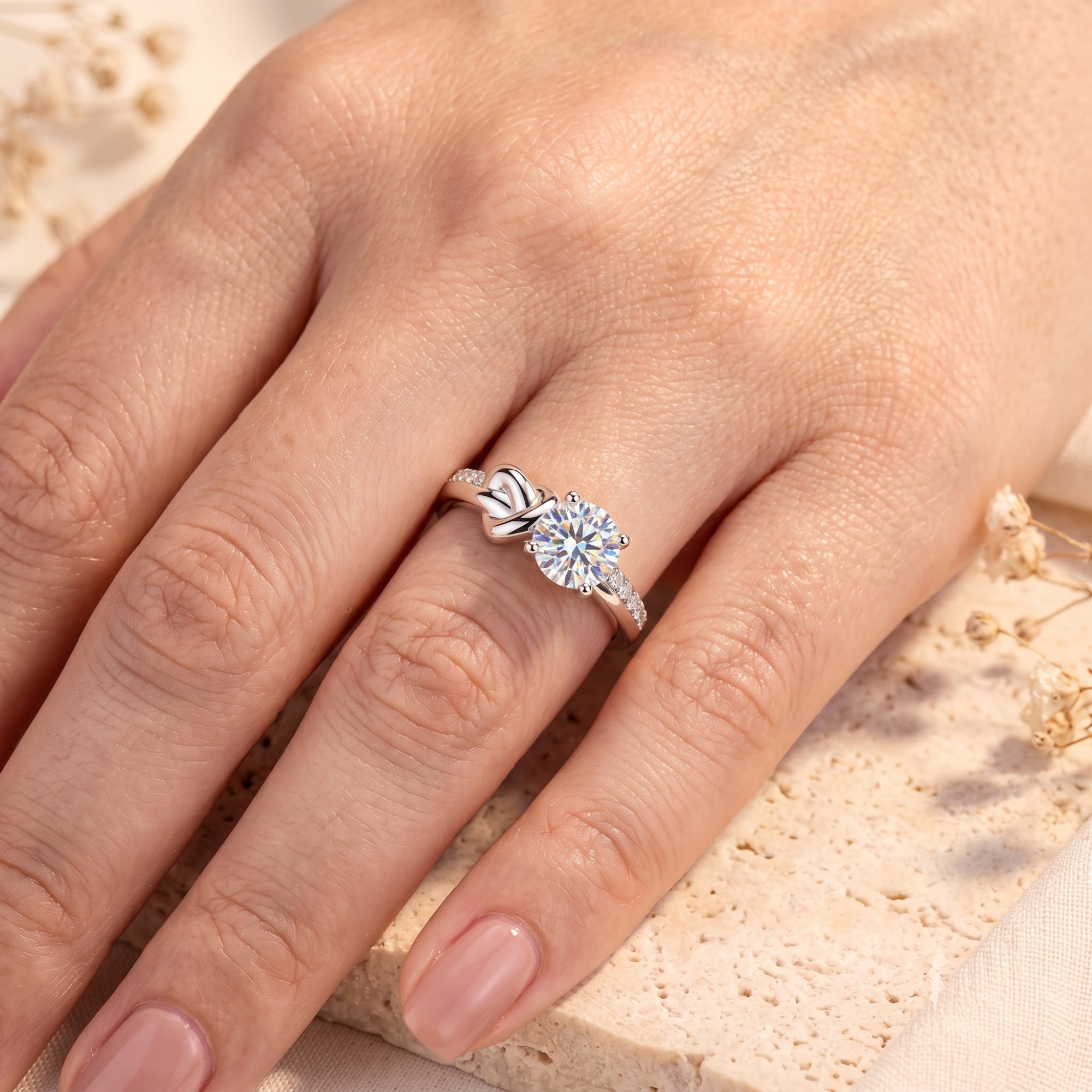 Silver devotion knot ring with round-cut solitaire stone worn on a woman's finger.